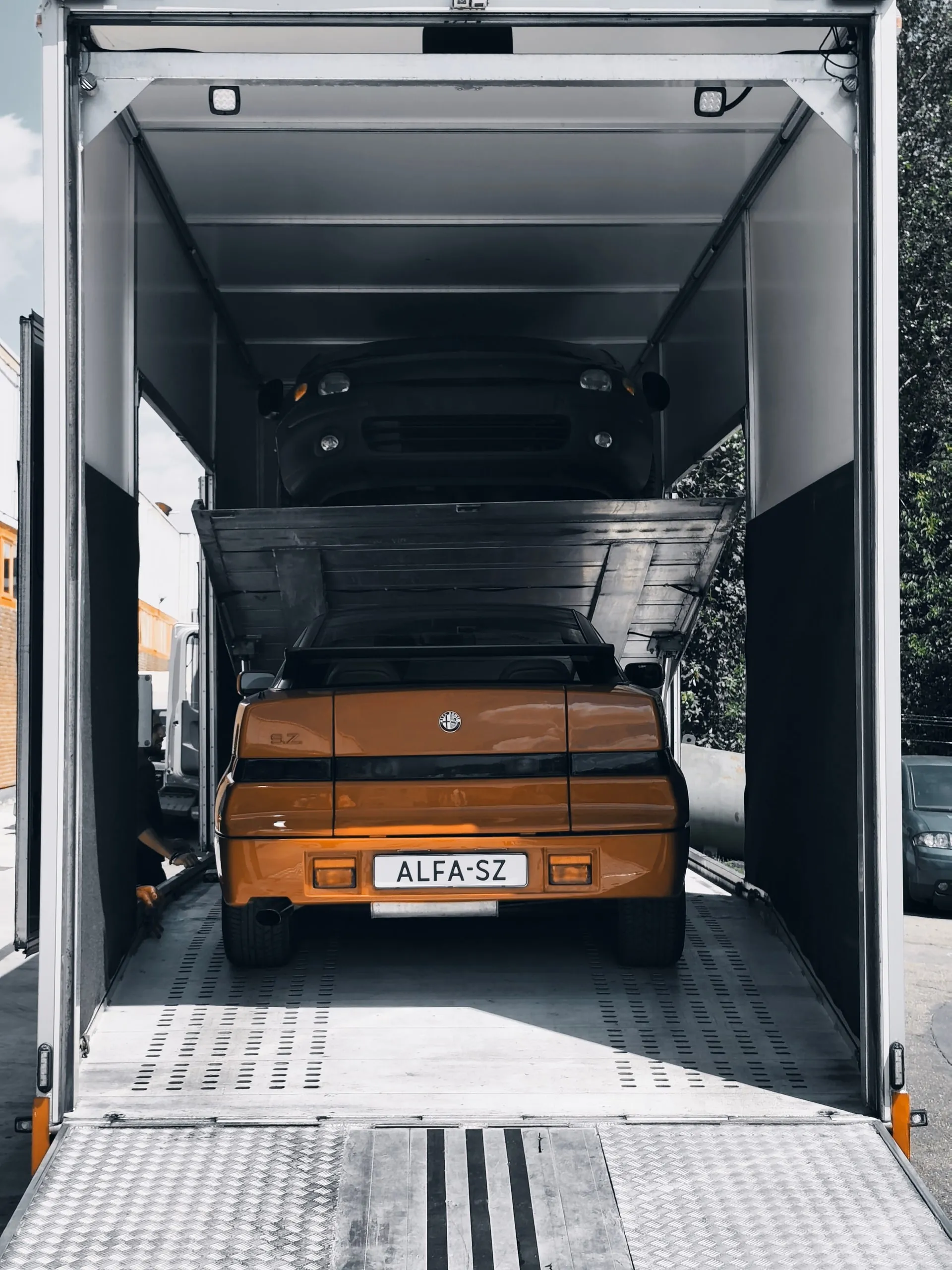 Achterzijde van een Alfa Romeo SZ vastgezet in een gesloten trailer