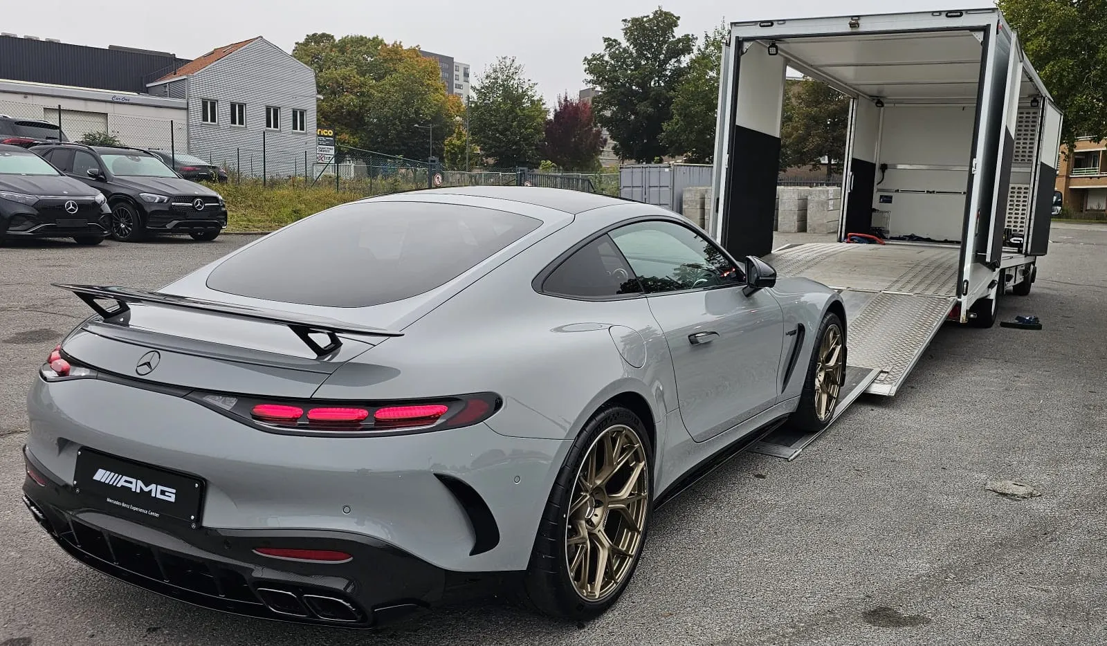 Grijze Mercedes-AMG GT aan de voet van de kleppen, achterdeur open