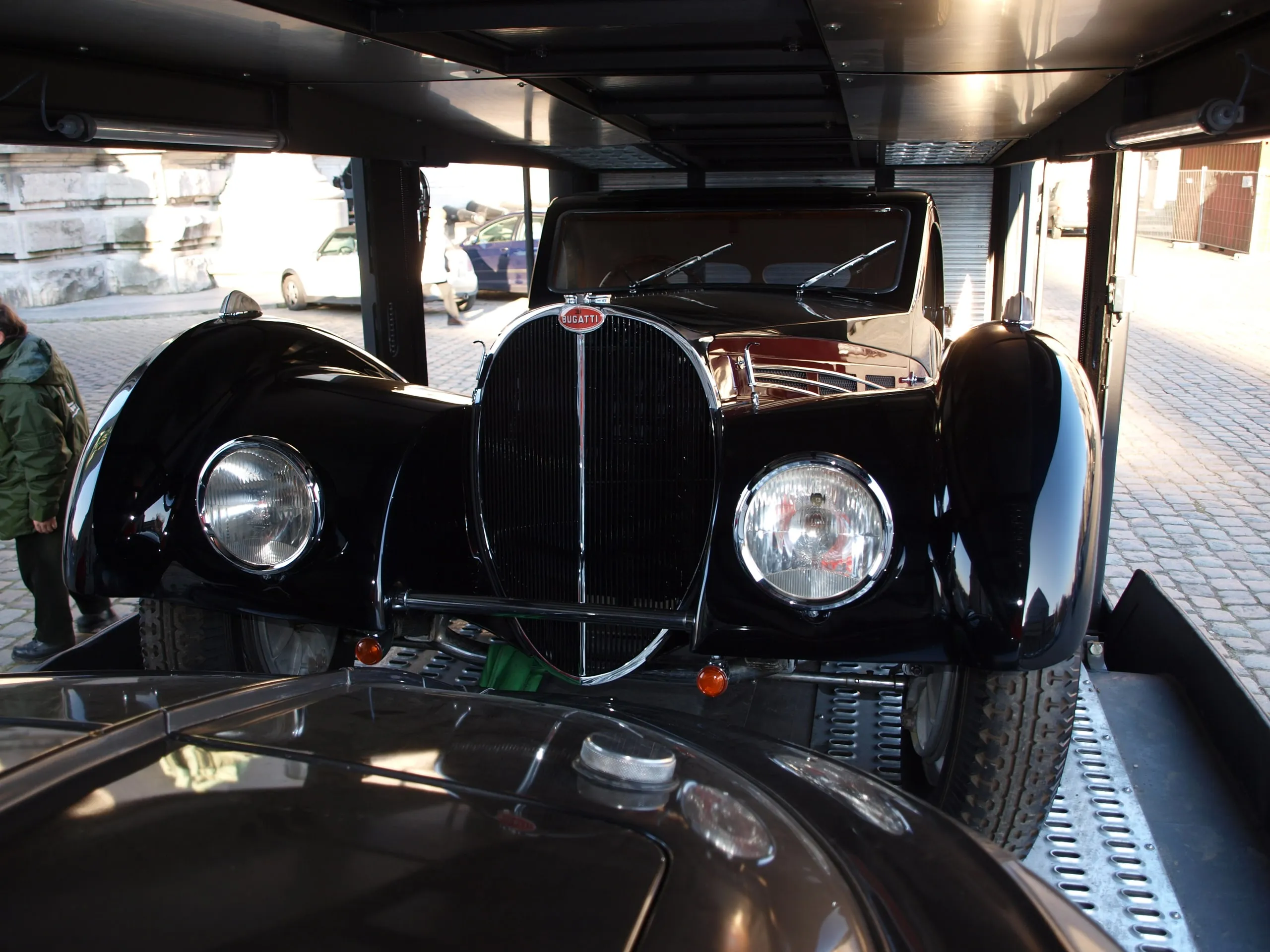 Voorzijde van een zwarte vooroorlogse Bugatti-coupé met hoefijzergrille in een transporter