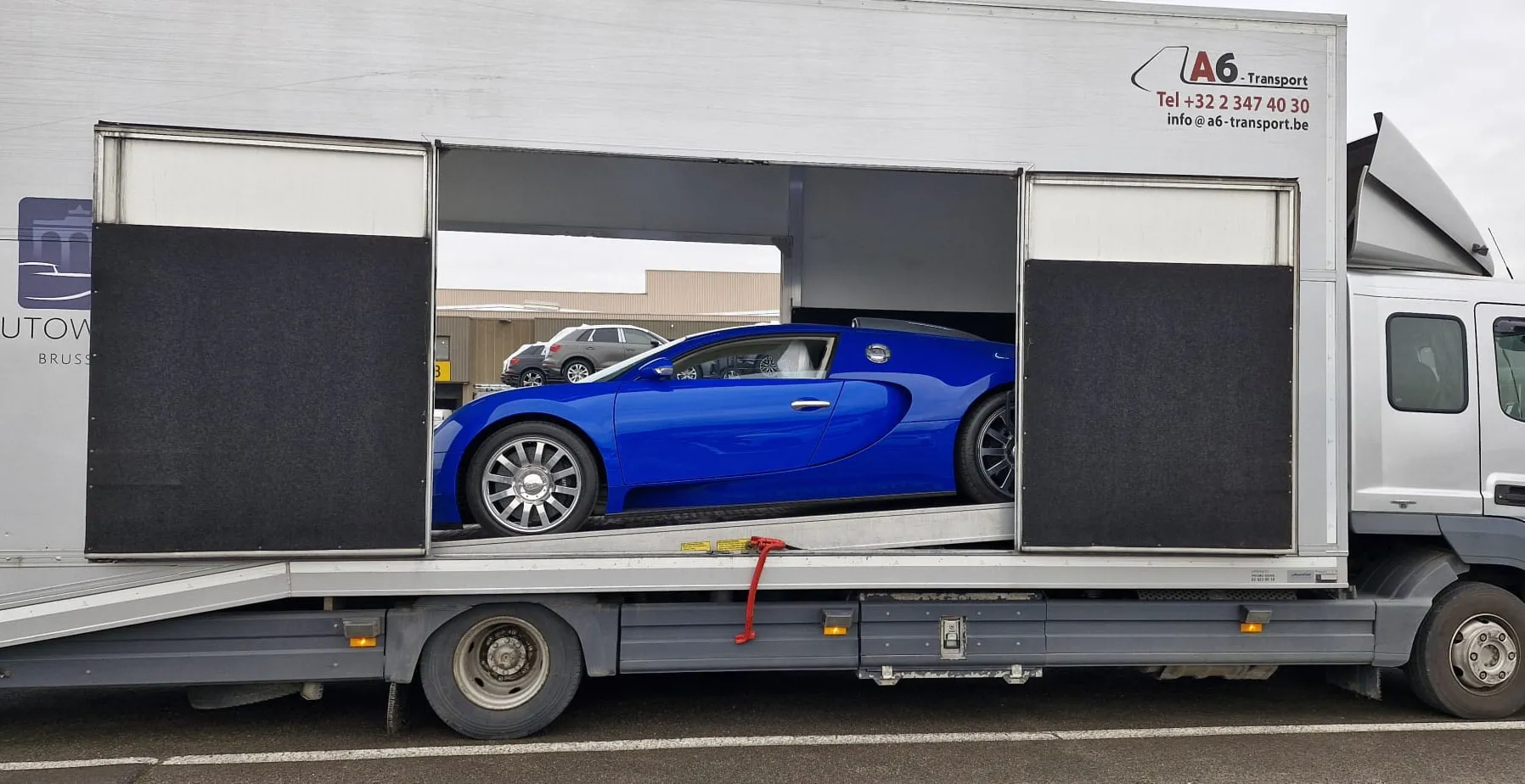 Blauwe Bugatti Veyron in de gesloten transporter, zijdeuren open bij het museum
