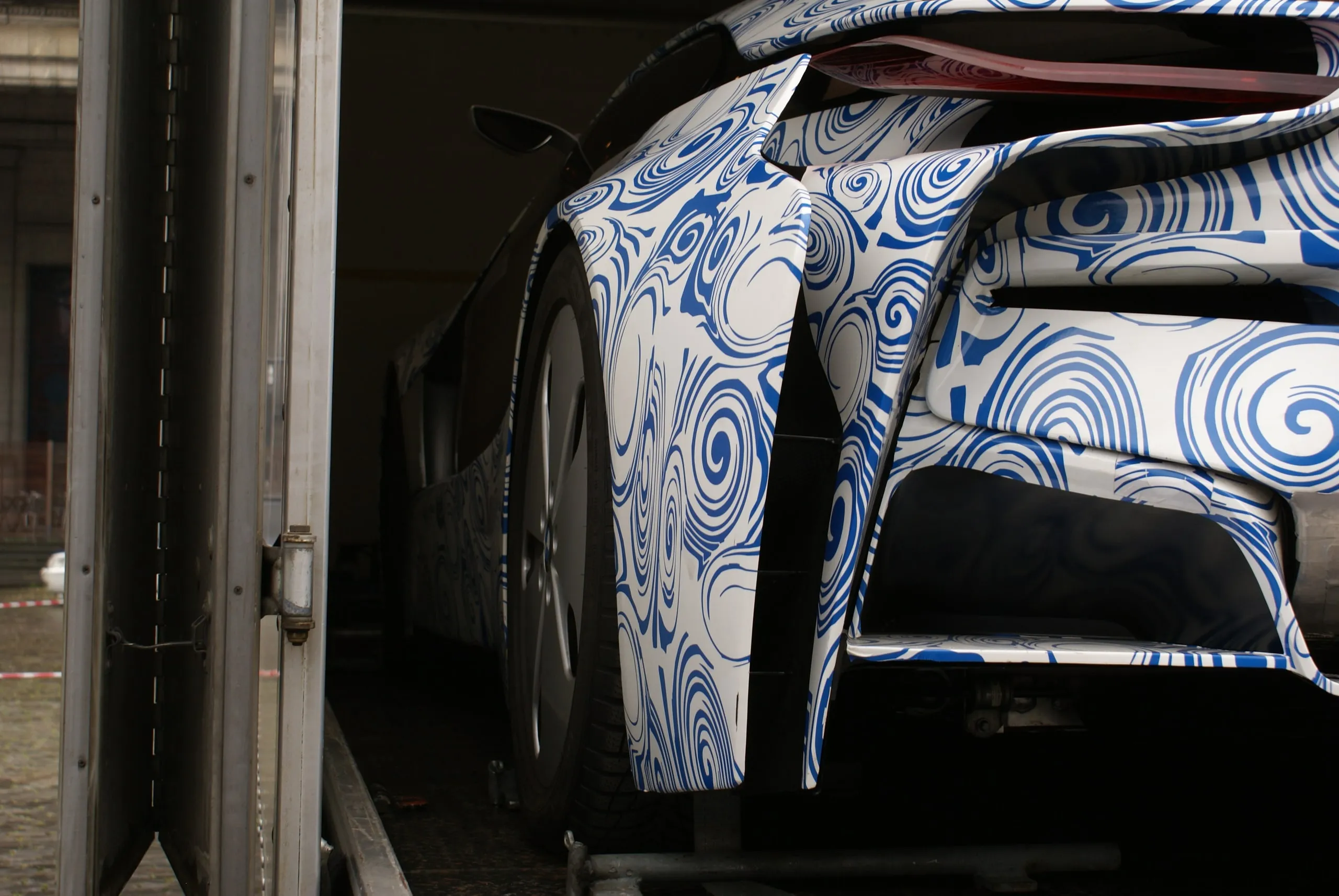 Flank van een conceptcar met camouflagewrap, verlicht in een donkere transporter