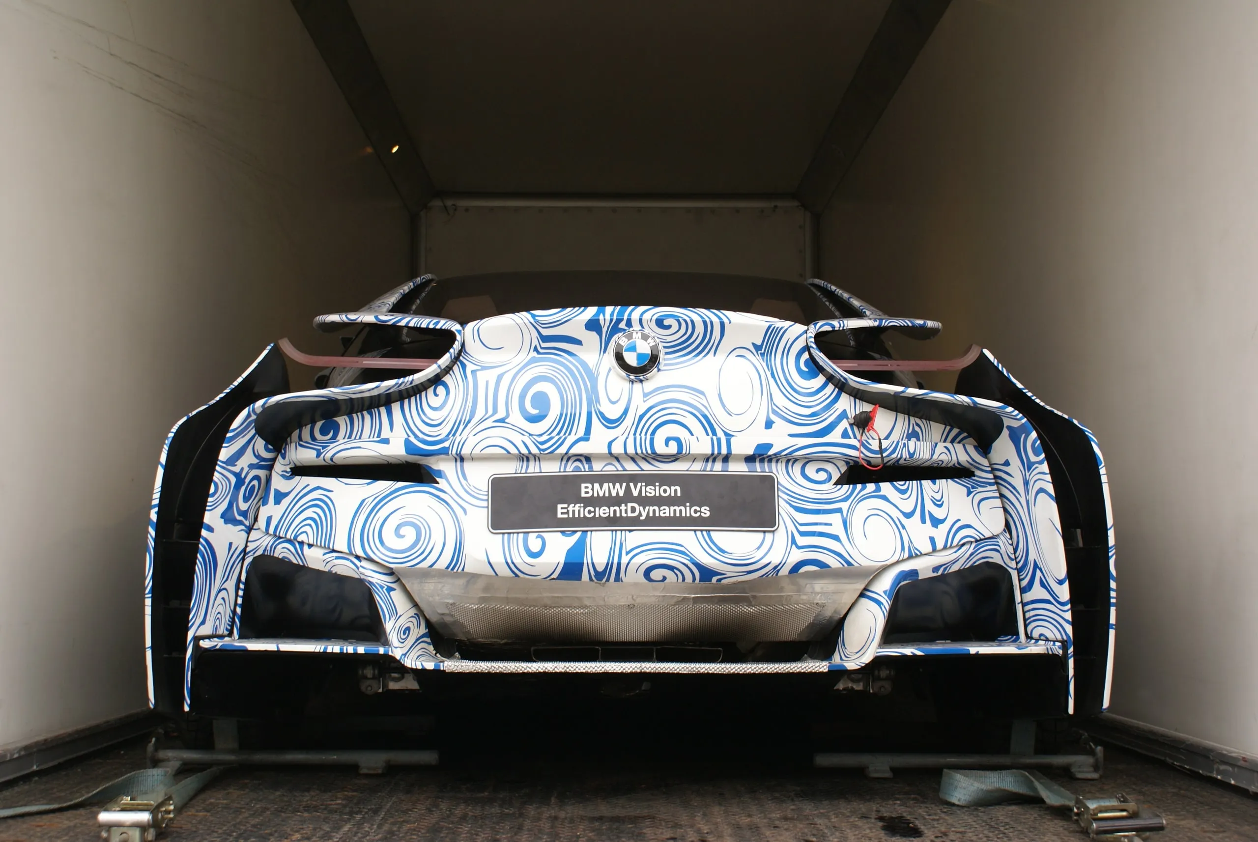Conceptcar met blauwe camouflagewrap in een gesloten transporter