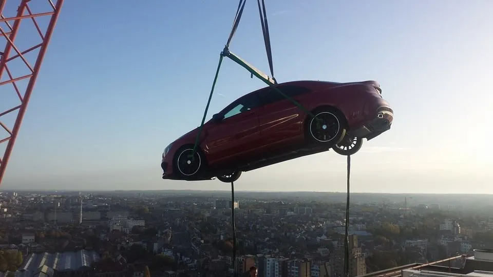 Donkerrode sedan in hijsbanden boven de skyline van de stad