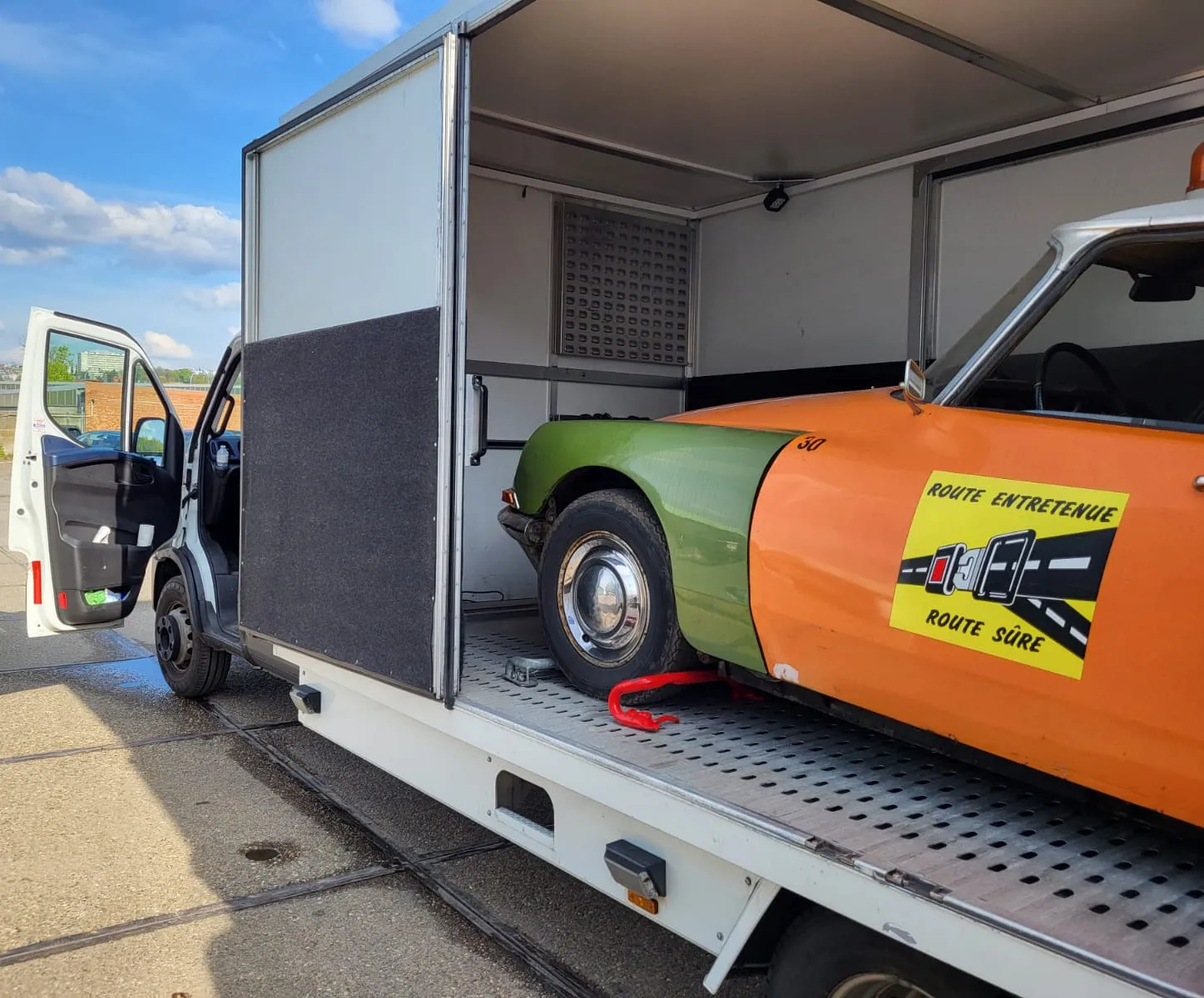 Citroën DS in oranje verkeersveiligheidsbelettering in een gesloten transporter