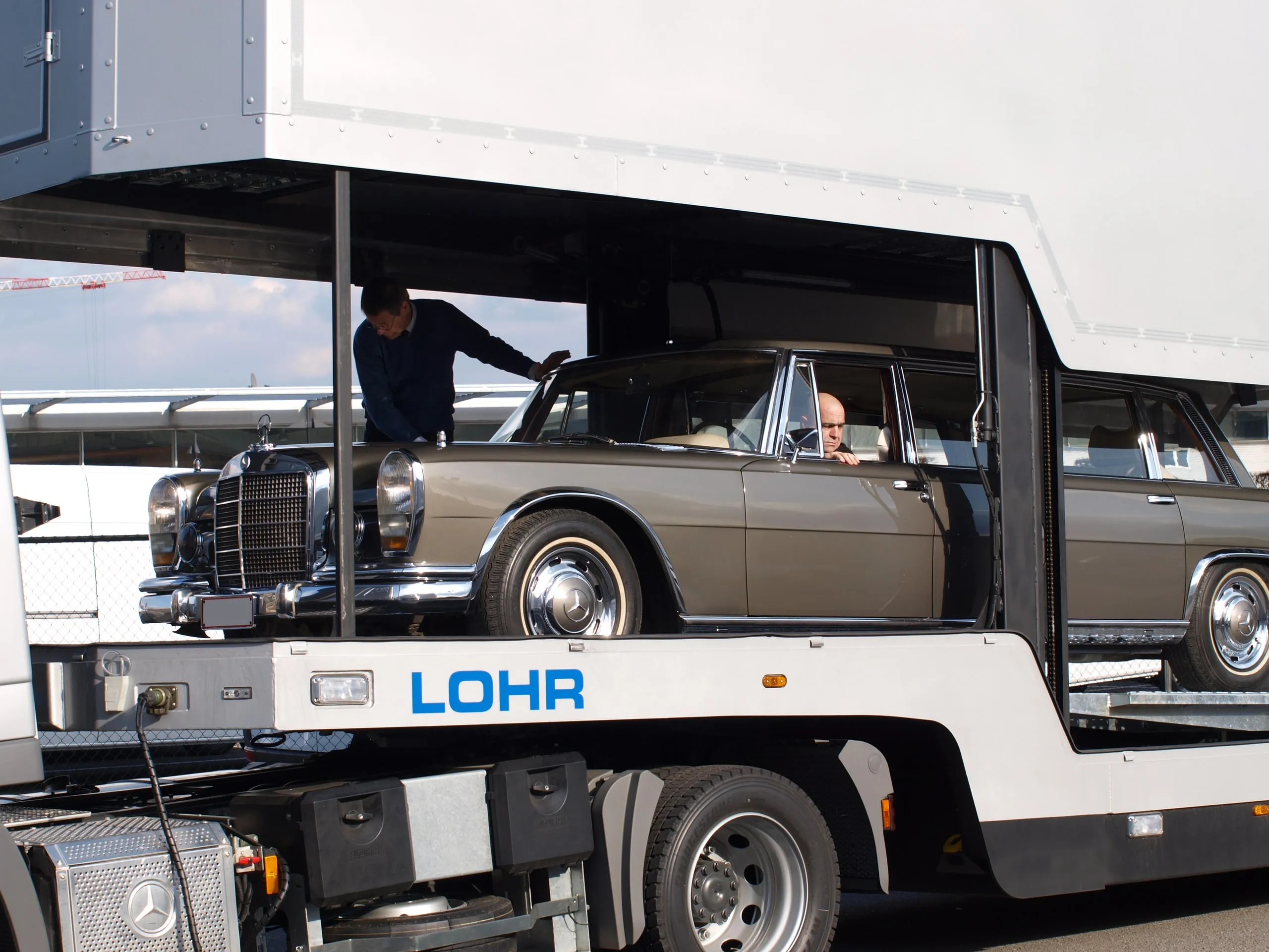 Klassieke Mercedes-coupé op het onderdek van een transporter met open flanken