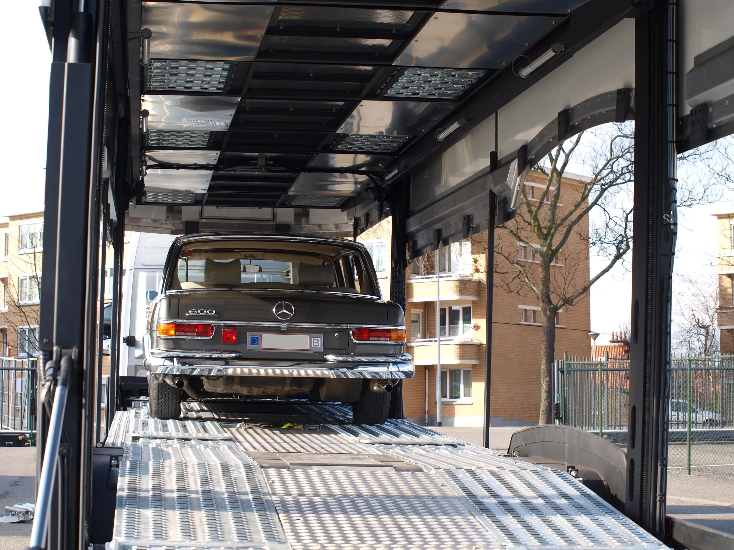 Achterzijde van een klassieke Mercedes-sedan in de transporter, de straat erachter
