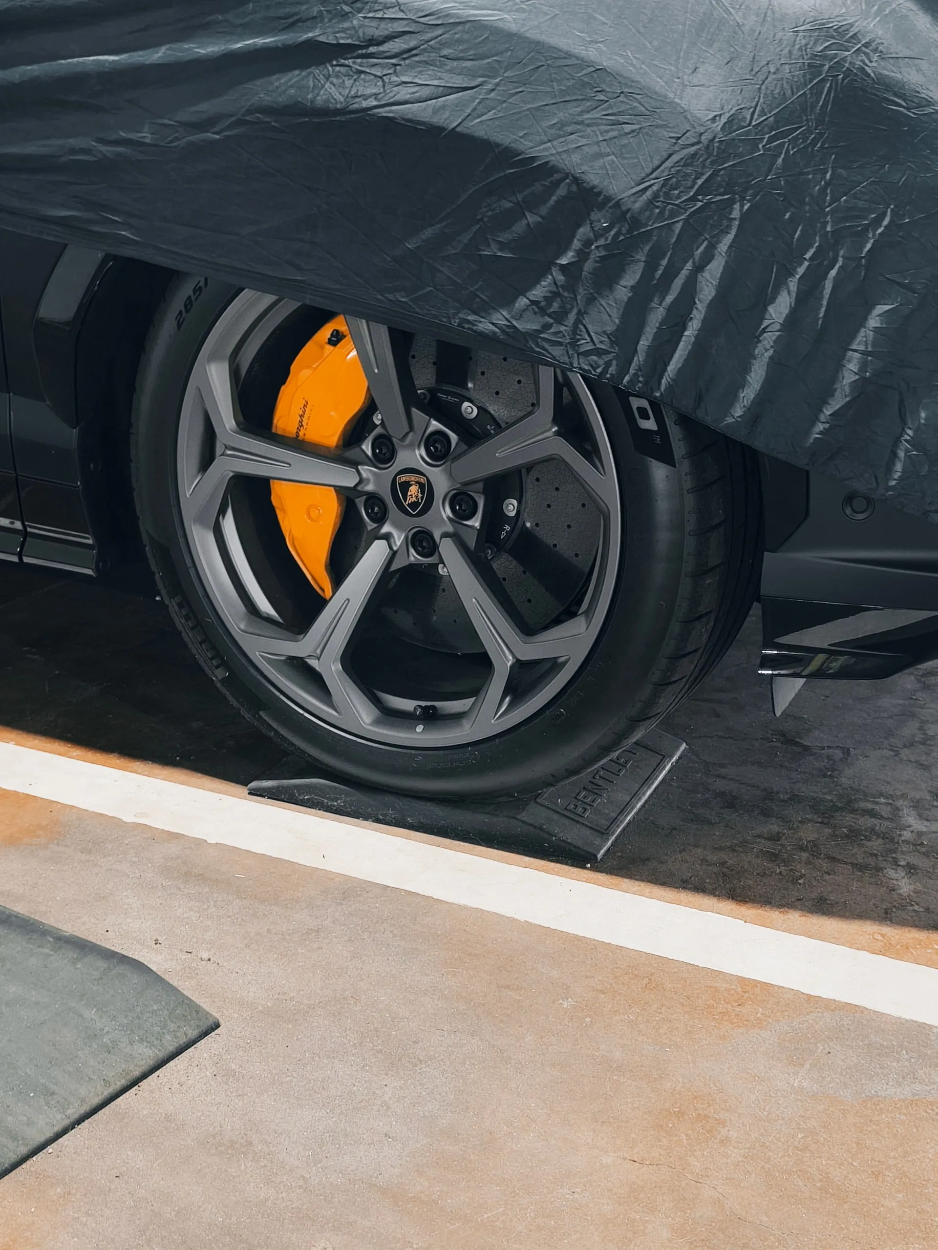 Wiel van een Lamborghini onder een hoes, op een matje dat de band beschermt