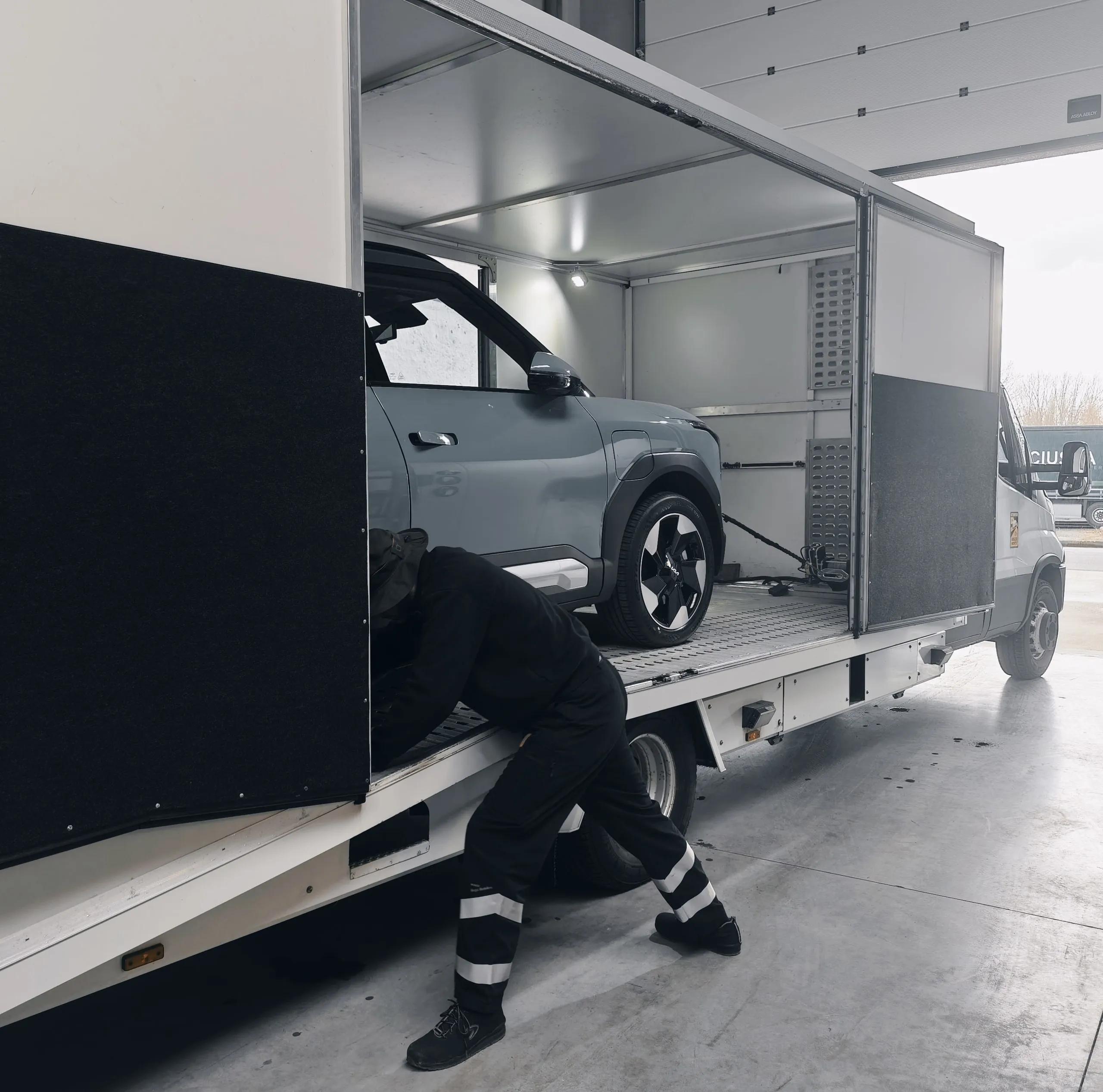 Medewerker zet een elektrische SUV vast op het dek van een transporter