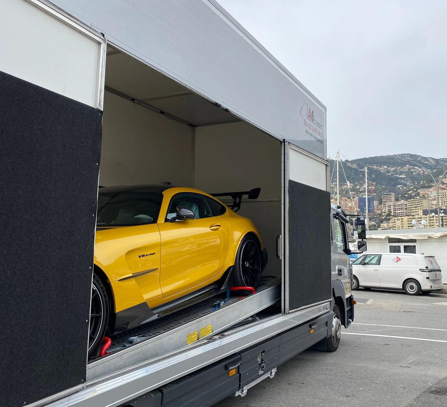 Gele AMG GT in een gesloten transporter, haven van Monaco erachter