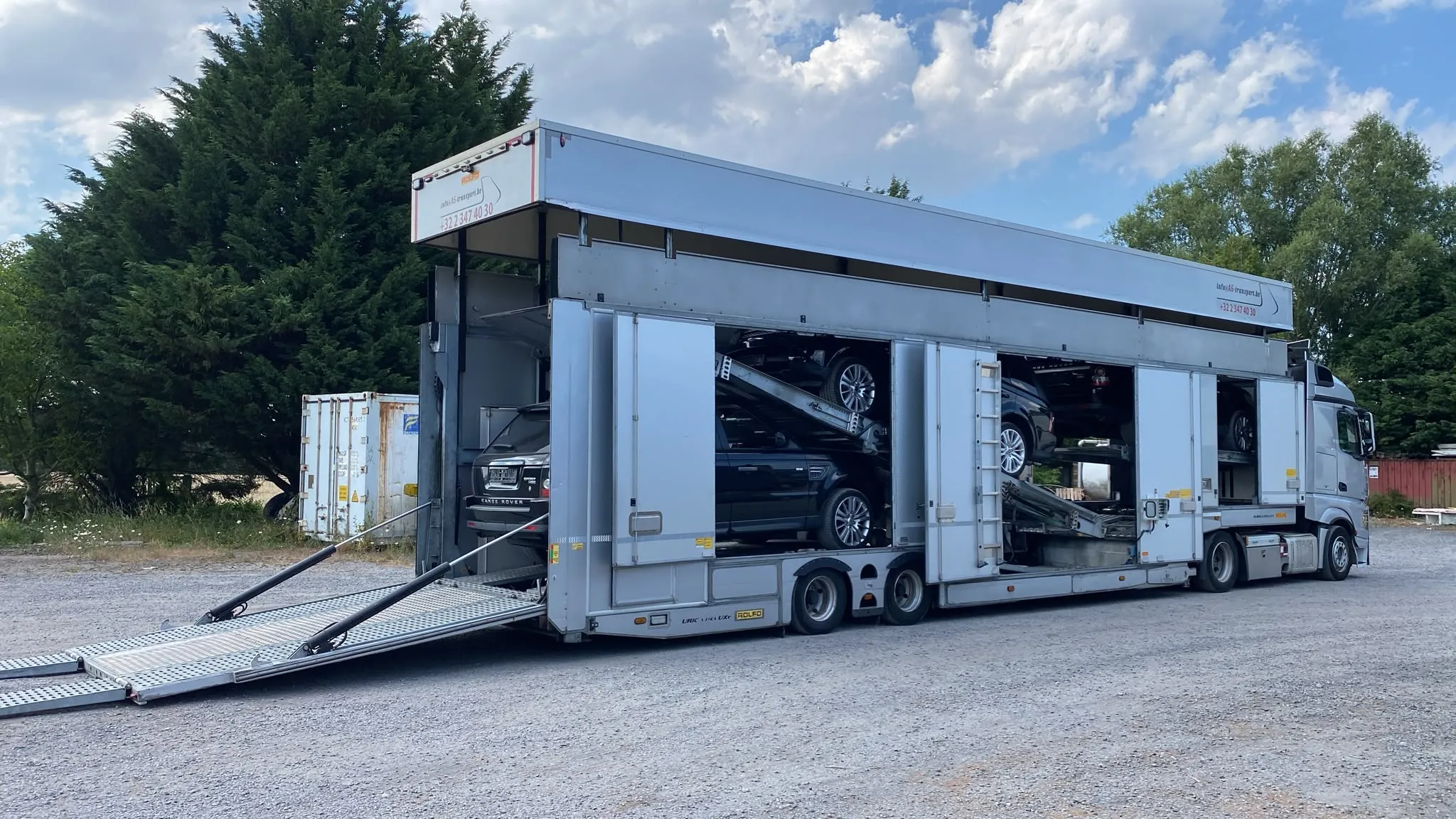Geschlossener Autotransporter mit ausgefahrenen Rampen, Range Rover an Bord