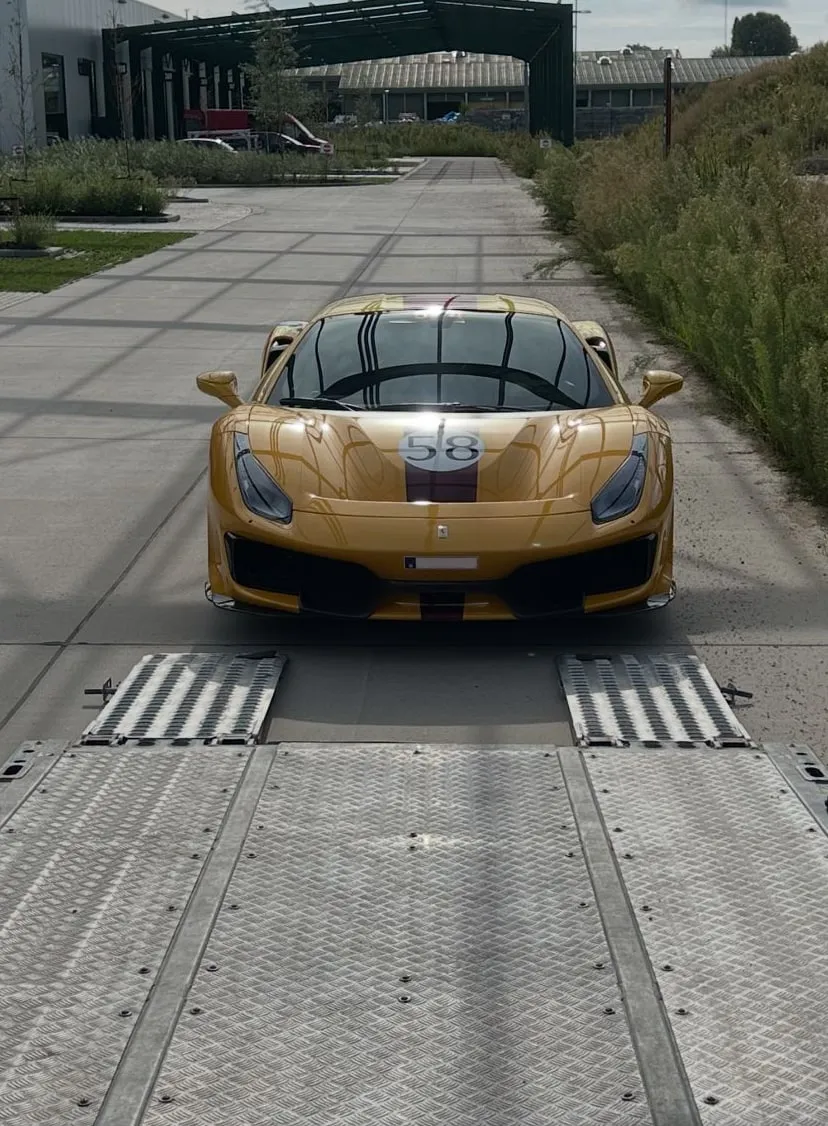 Gele Ferrari 488 Pista voor de neergelaten kleppen van een gesloten transporter