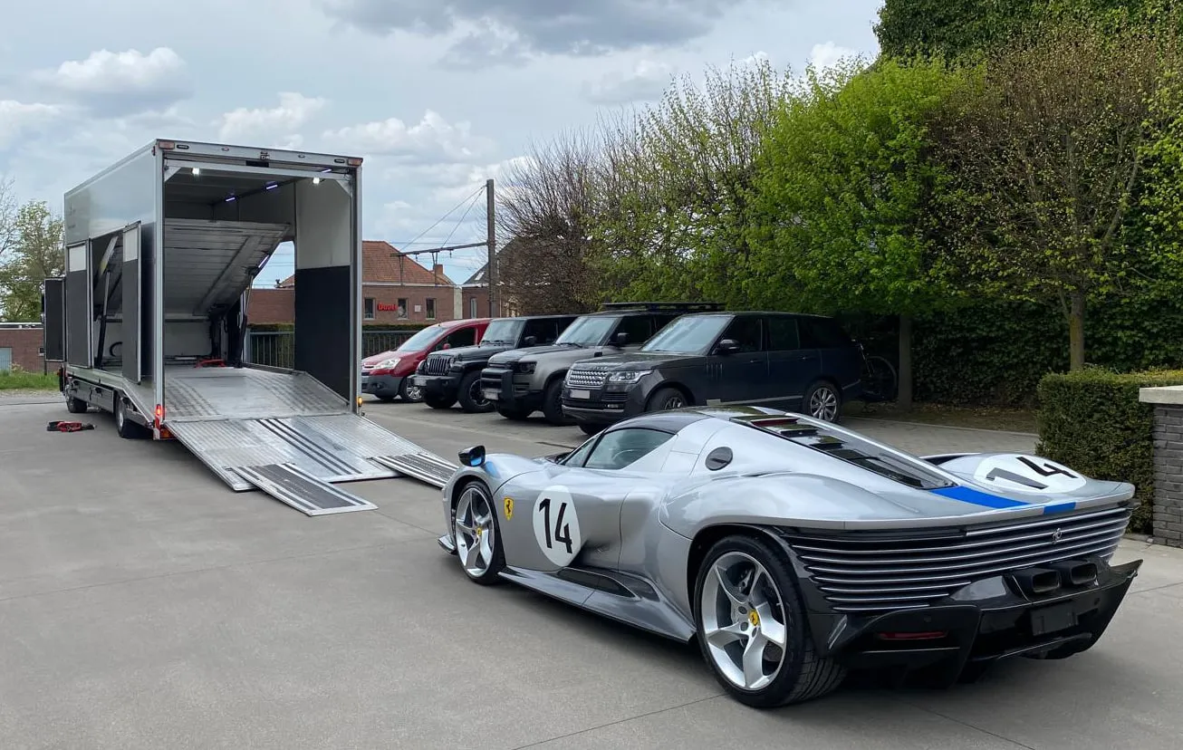 Zilveren Ferrari Daytona SP3 naast de gesloten transporter, kleppen neer