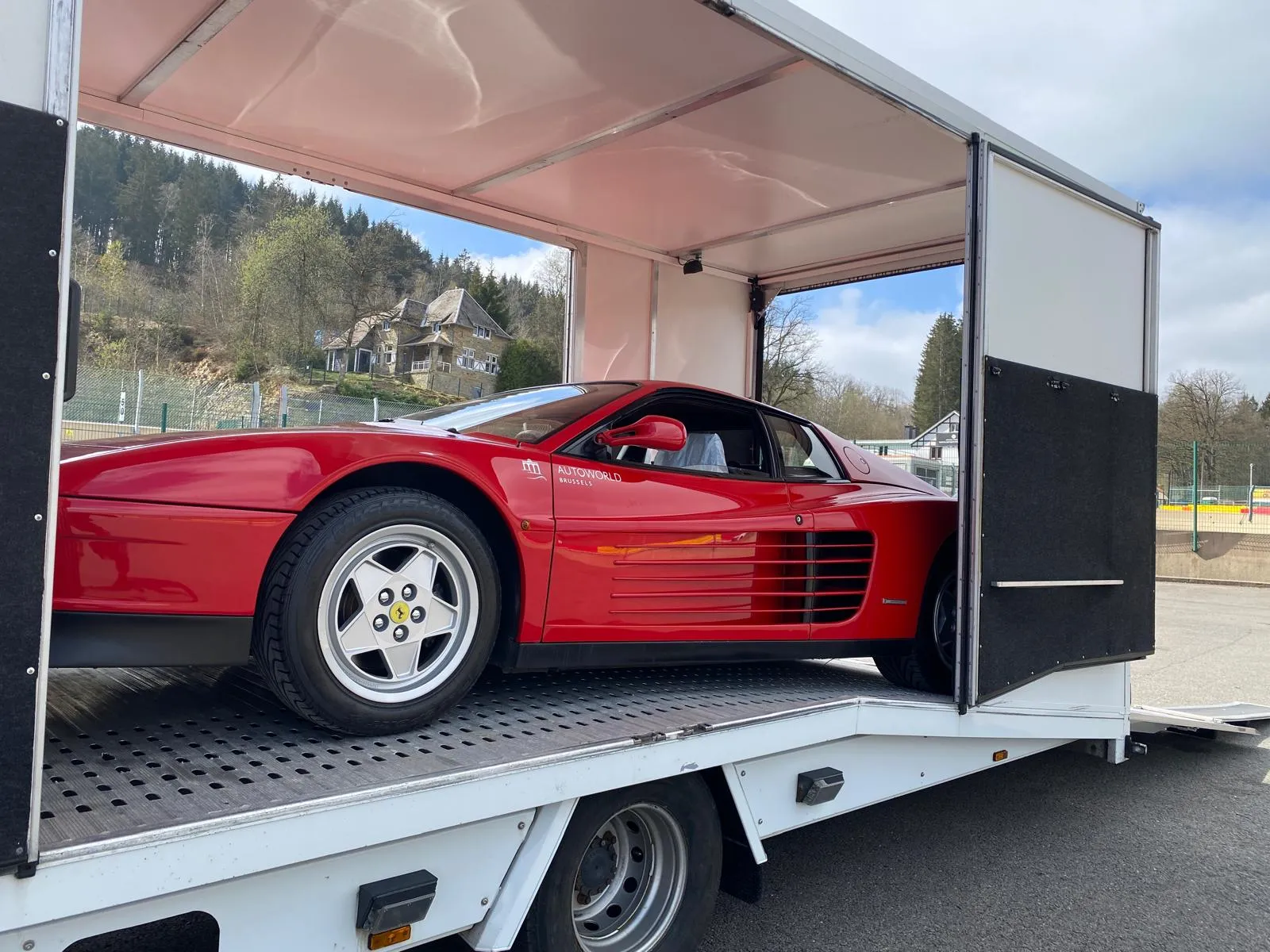 Rode Ferrari Testarossa in de gesloten transporter op een circuit