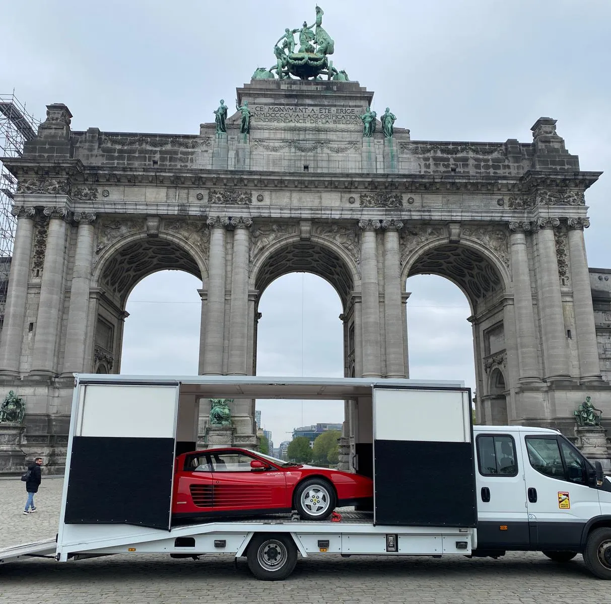 Rode Ferrari Testarossa in een gesloten transporter bij de Jubelparkboog
