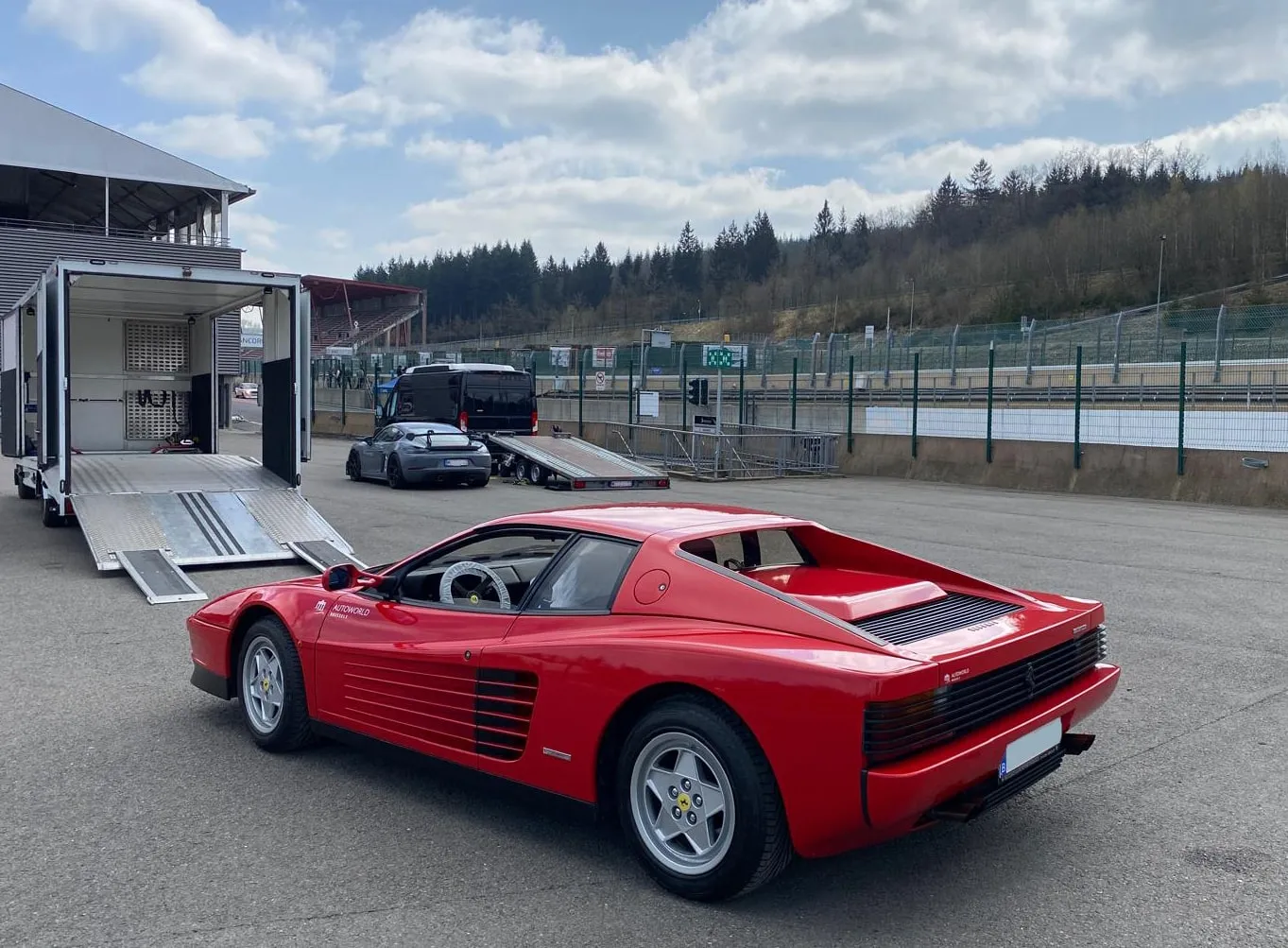 Rode Ferrari Testarossa gelost in de paddock van een circuit, kleppen neer