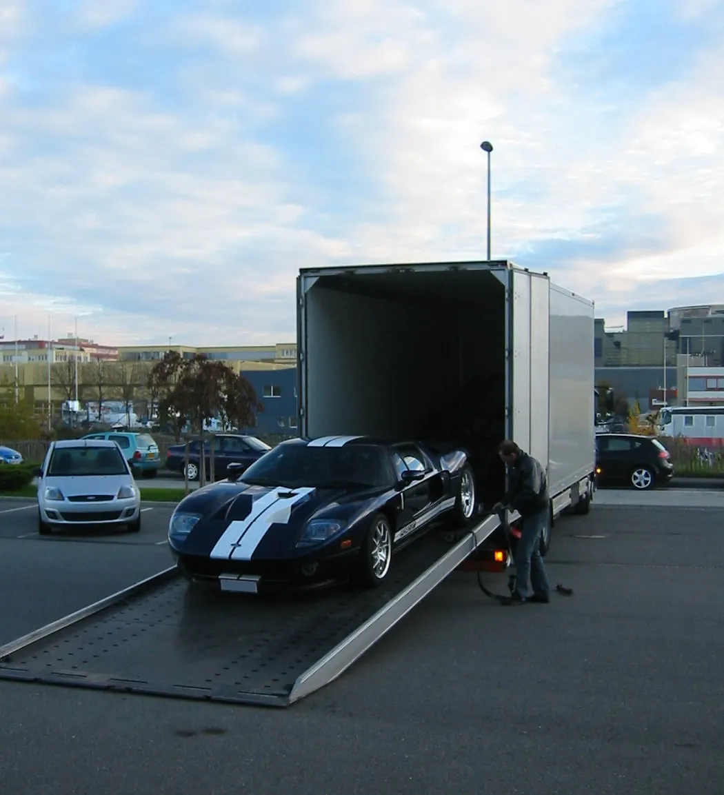 Ford GT aan de voet van de platen van een gesloten transporter bij schemering
