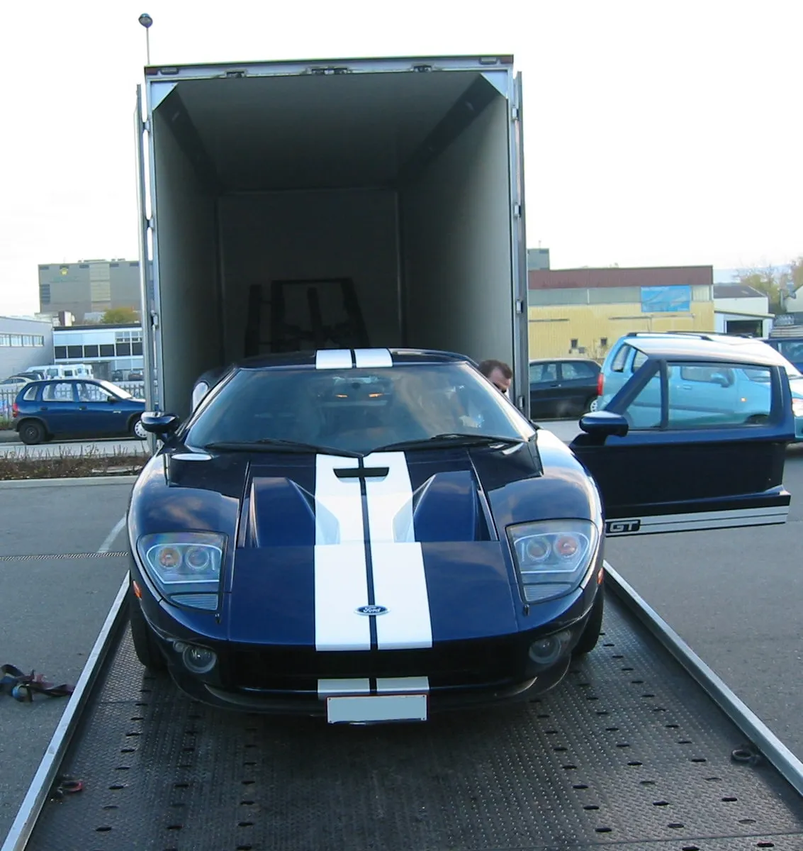 Blauwe Ford GT met de neus vooruit geladen in een gesloten kastentransporter