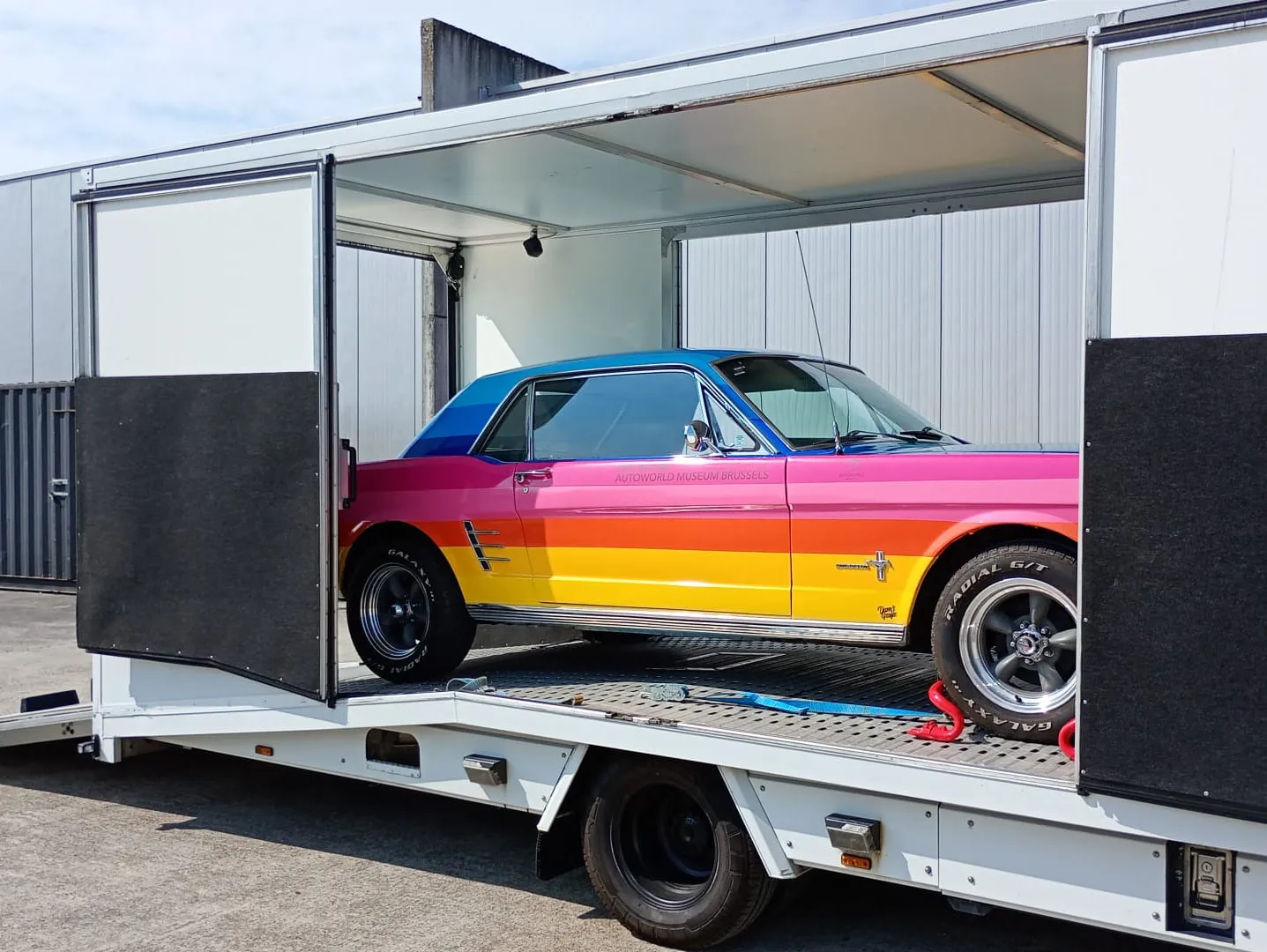 Veelkleurige Ford Mustang art car in profiel in een gesloten transporter