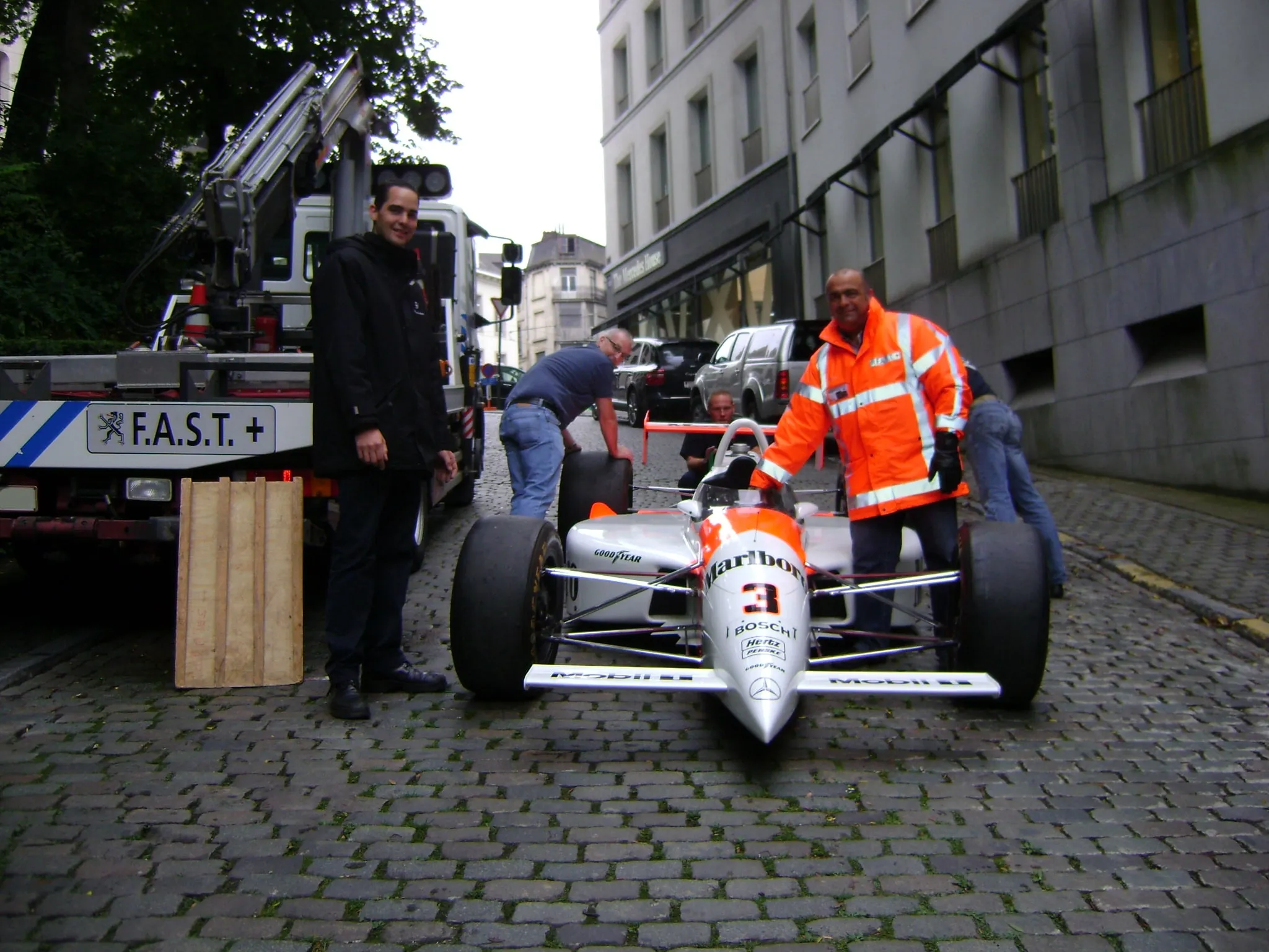 Formule 1-wagen met de hand voortgeduwd door een Brusselse kasseienstraat