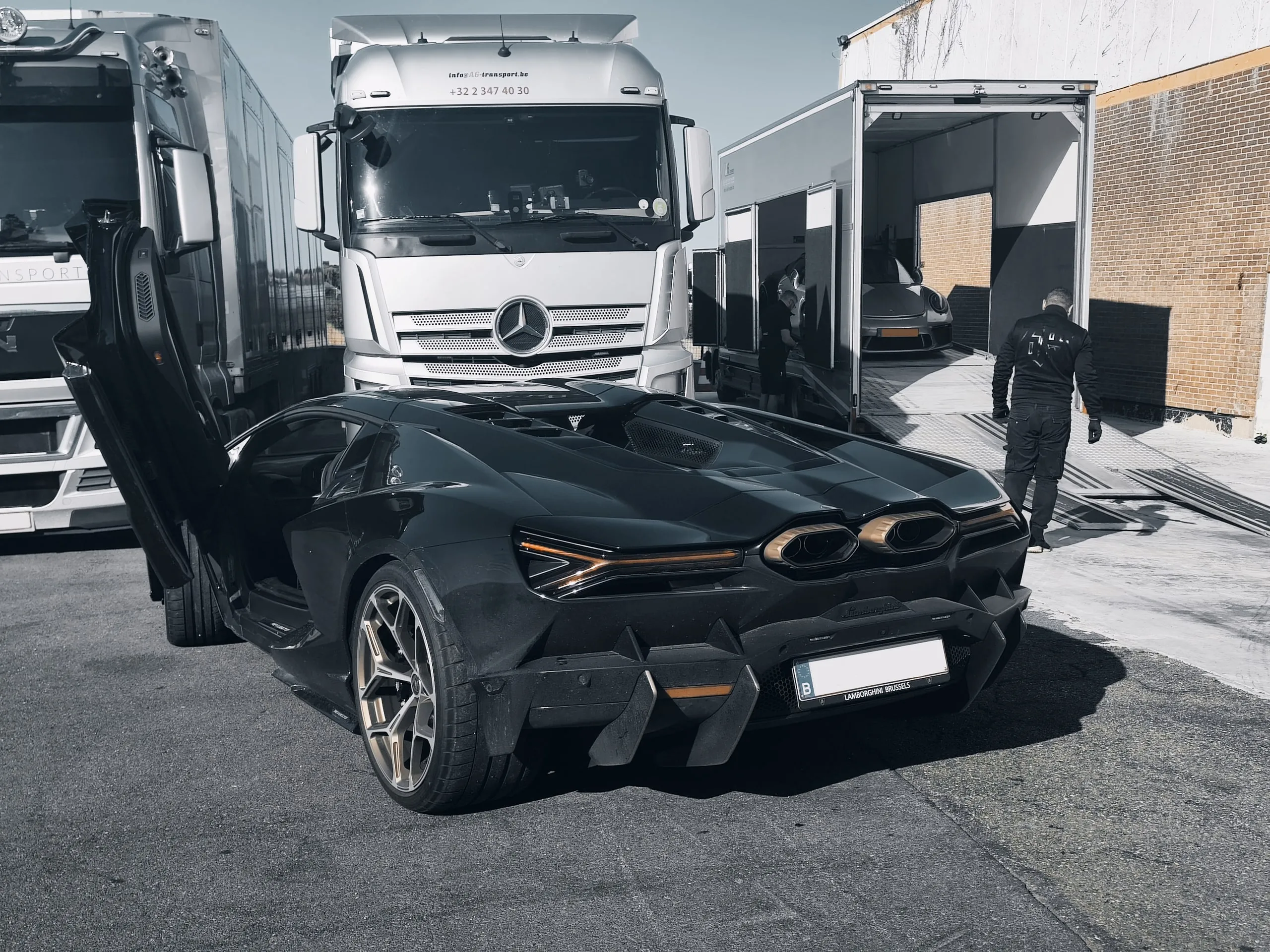 Lamborghini Revuelto met open vleugeldeuren naast de transporter