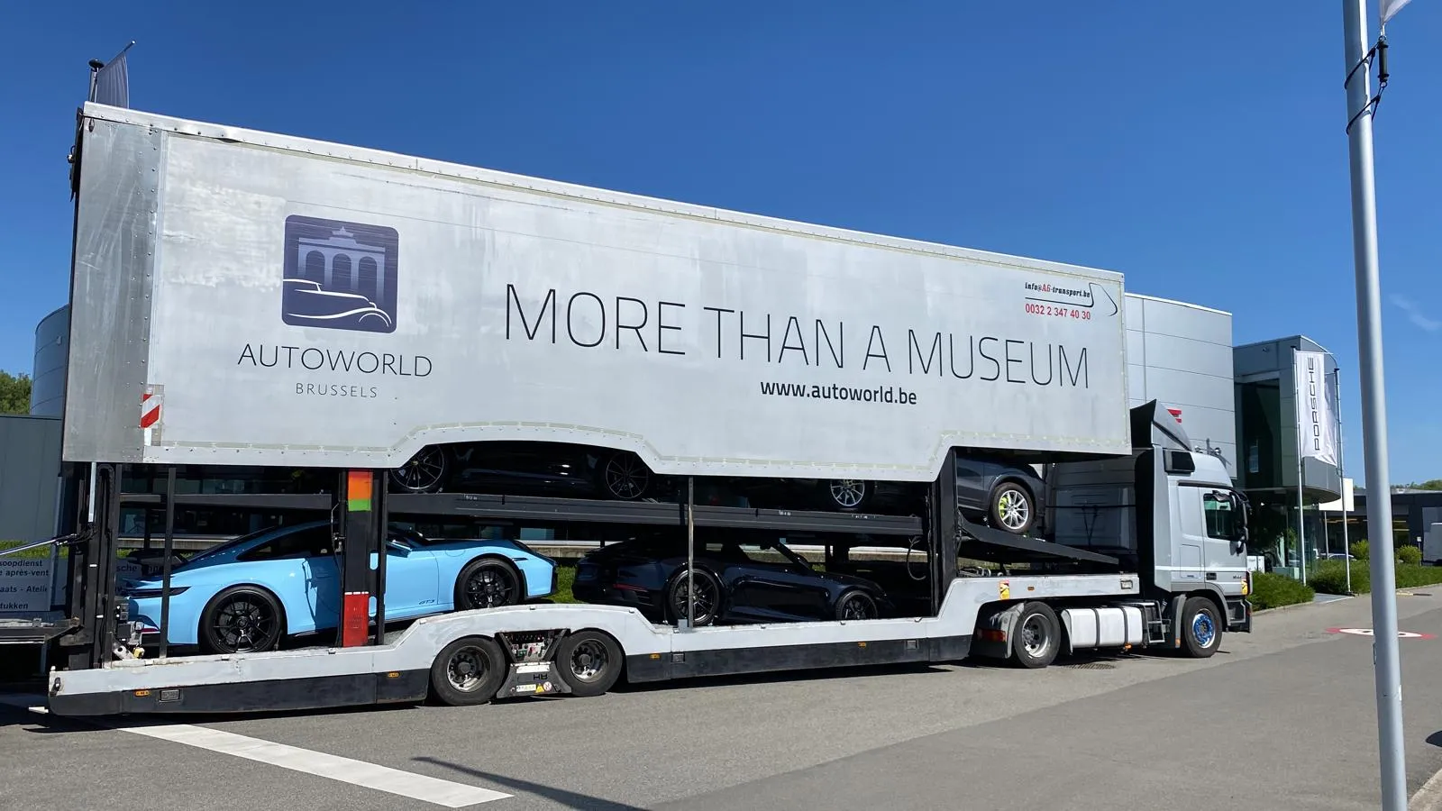 Lichtblauwe Porsche 911 GT3 op het onderdek van de museumtransporter