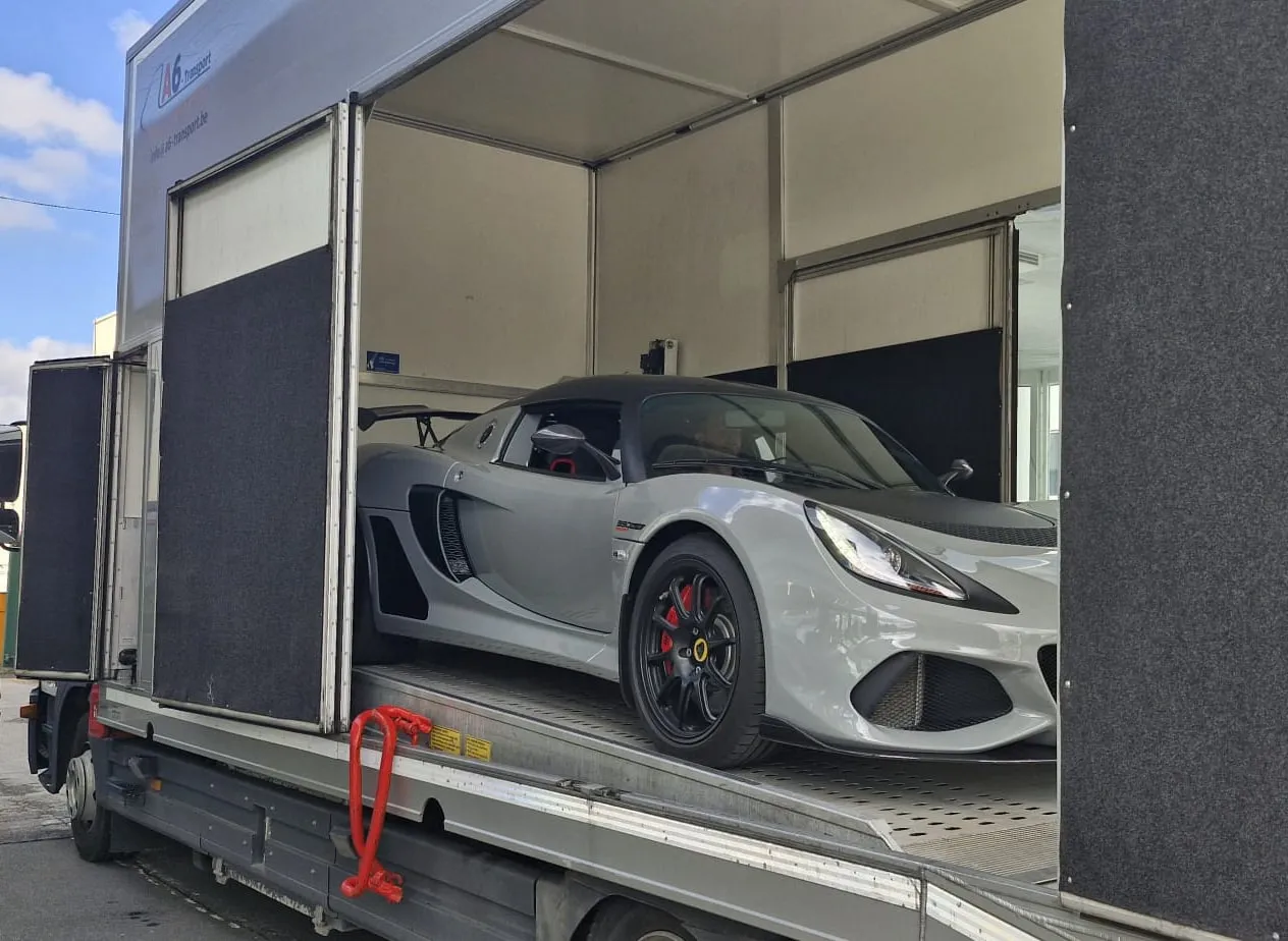 Grijze Lotus Exige met vleugel in de gesloten truck, zijdeur open