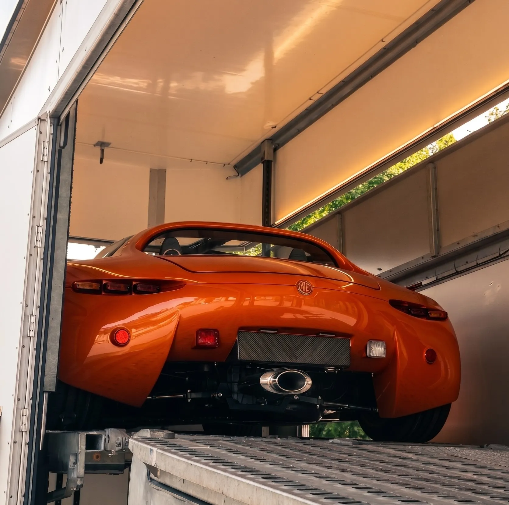 Oranje roadster op het bovendek van een gesloten transporter