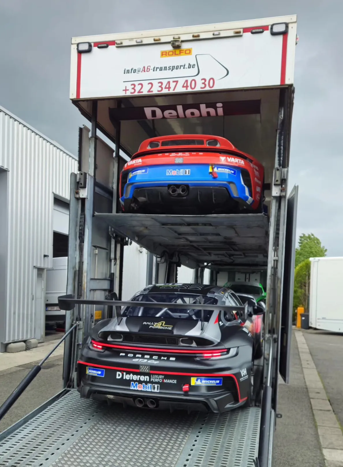 Porsche 911 GT3 Cup-racewagens op de dekken van een gesloten transporter, achterzijde open
