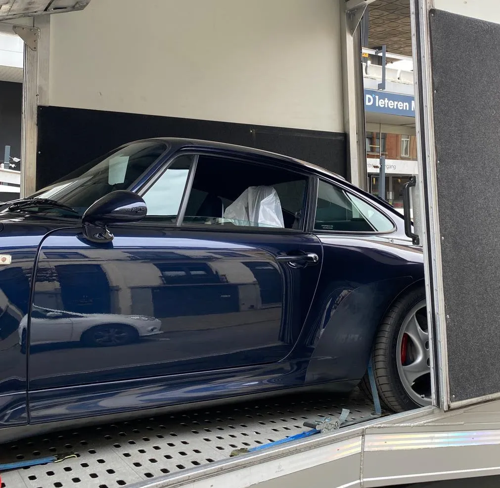 Blauwe Porsche 993 Turbo gezien door de zijdeur van de transporter
