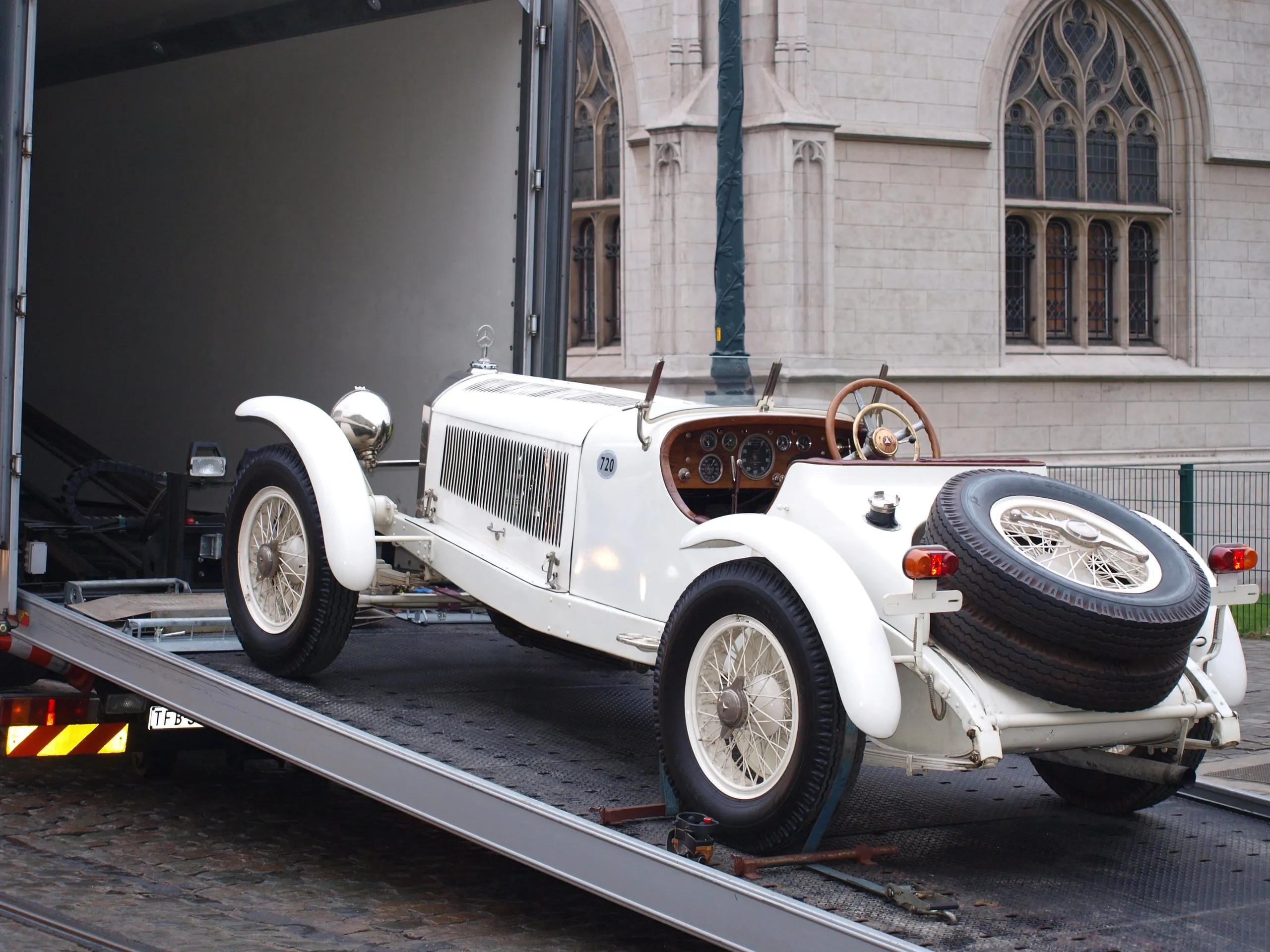 Witte vooroorlogse Mercedes SSK op de plaat van een gesloten transporter voor een kerk