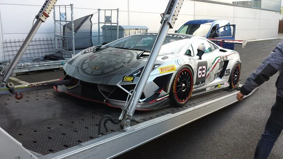 Lamborghini in racekleuren wordt in de regen op een oplegger geladen
