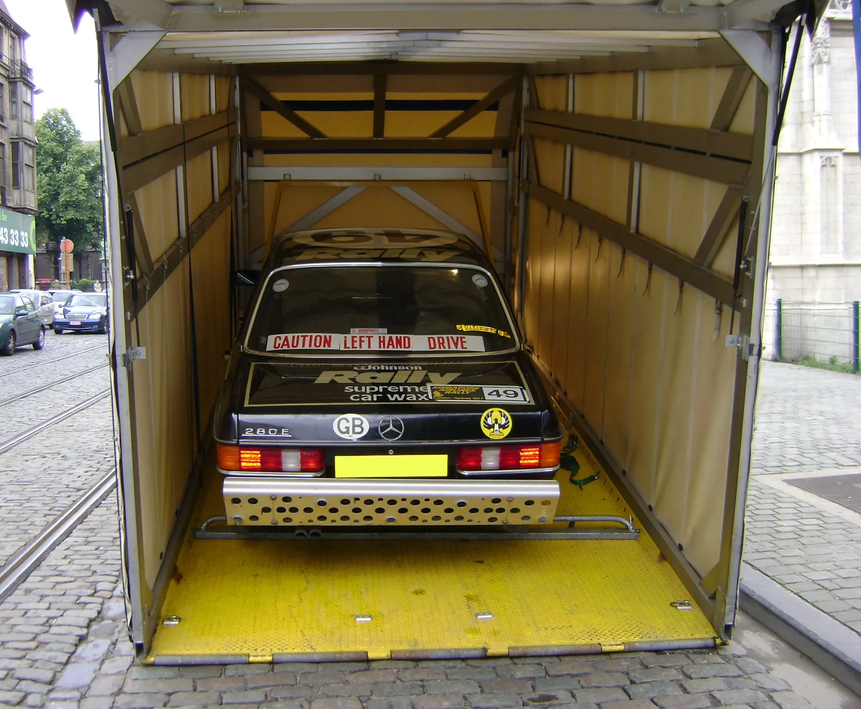 Beletterde Mercedes-racewagen in een overdekte bestelwagen met gele vloer