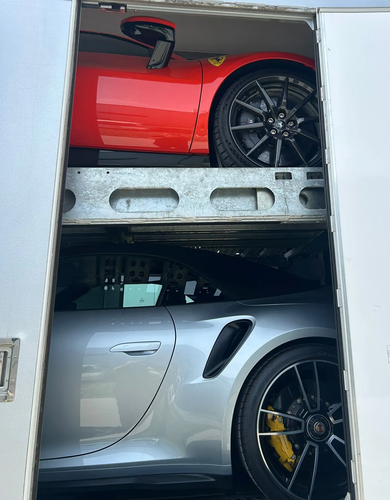 Rode Ferrari op het bovendek, zilveren Porsche 911 Turbo S op het onderdek