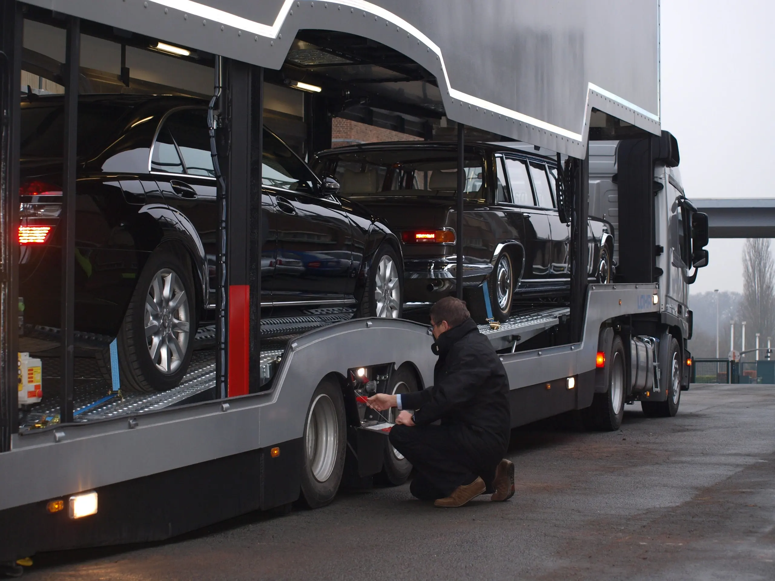 Crewmitglied kniet, um einen klassischen Mercedes auf dem unteren Deck zu zurren