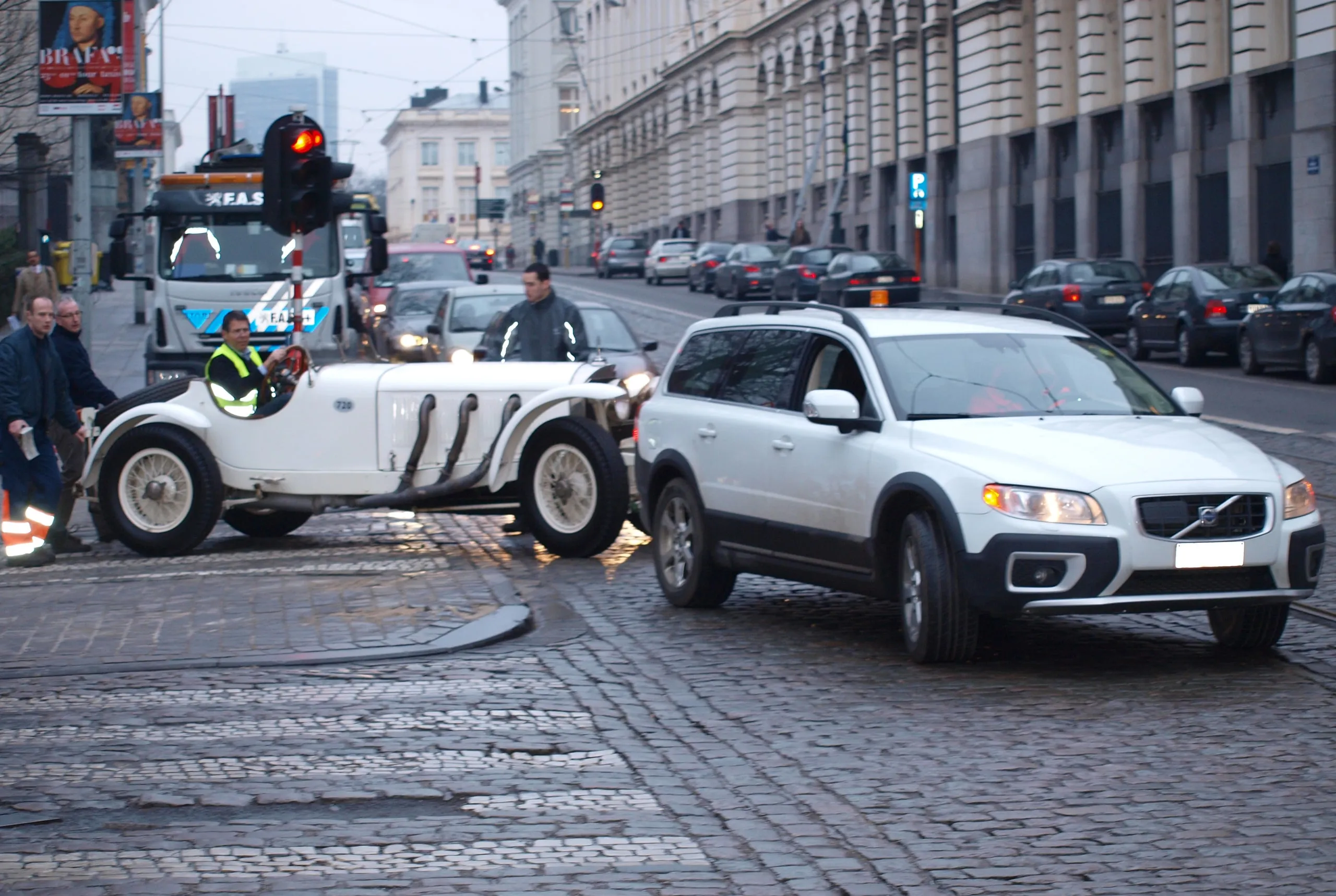Vooroorlogse zilveren grandprixwagen steekt een Brusselse straat over tussen het verkeer