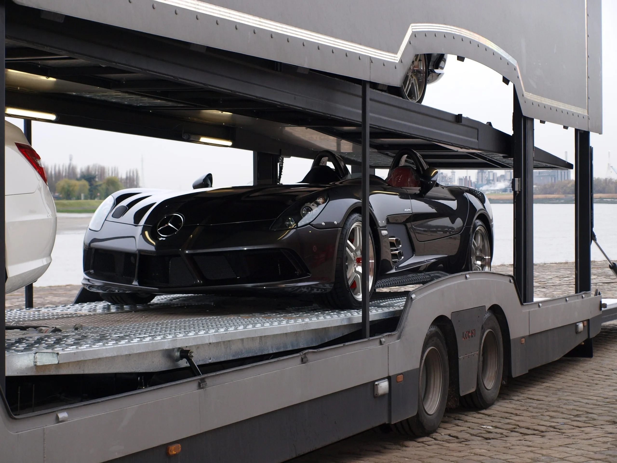 Mercedes SLR McLaren en een witte coupé op de dekken van de transporter aan het water