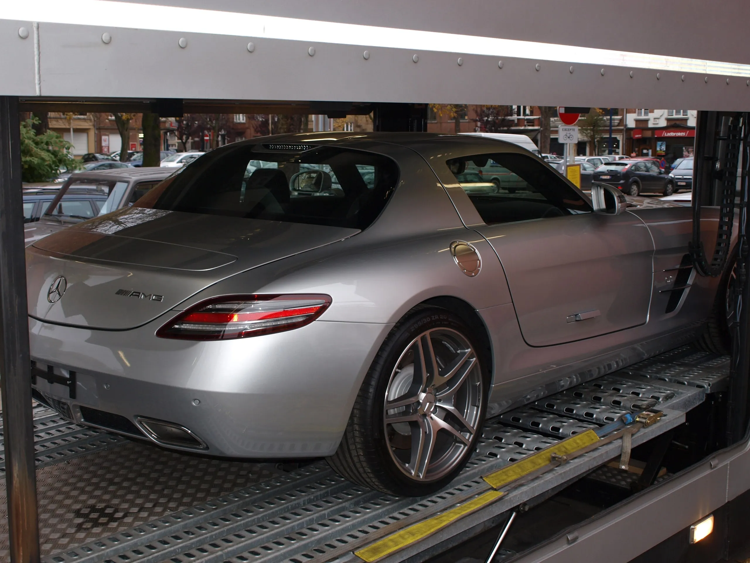 Zilverkleurige Mercedes SLS AMG naast een 300 SL Gullwing in een transporter