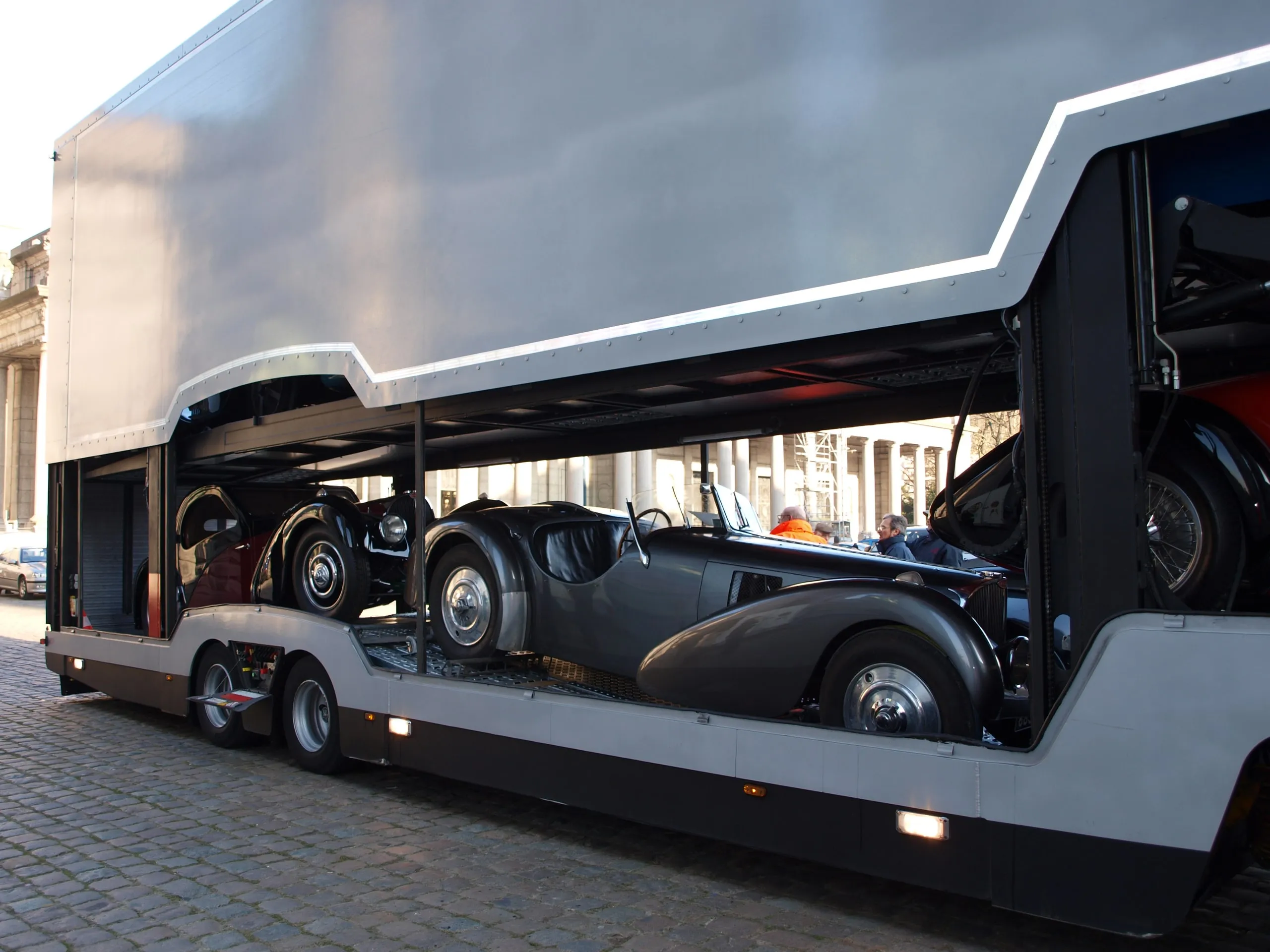 Gestroomlijnde grijze vooroorlogse Bugatti op het onderdek, flank van de transporter open