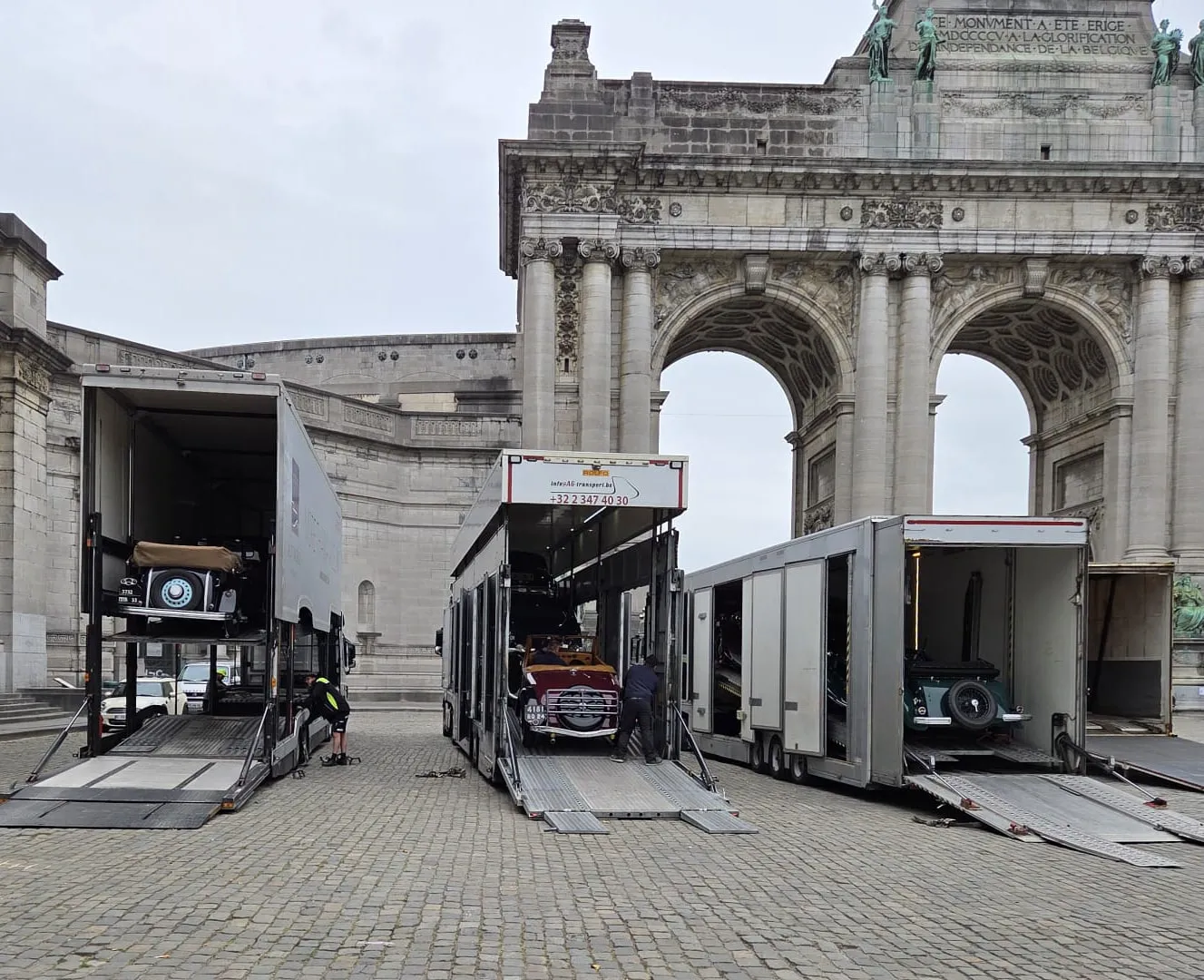 Trois camions porte-voitures déchargeant devant le Cinquantenaire