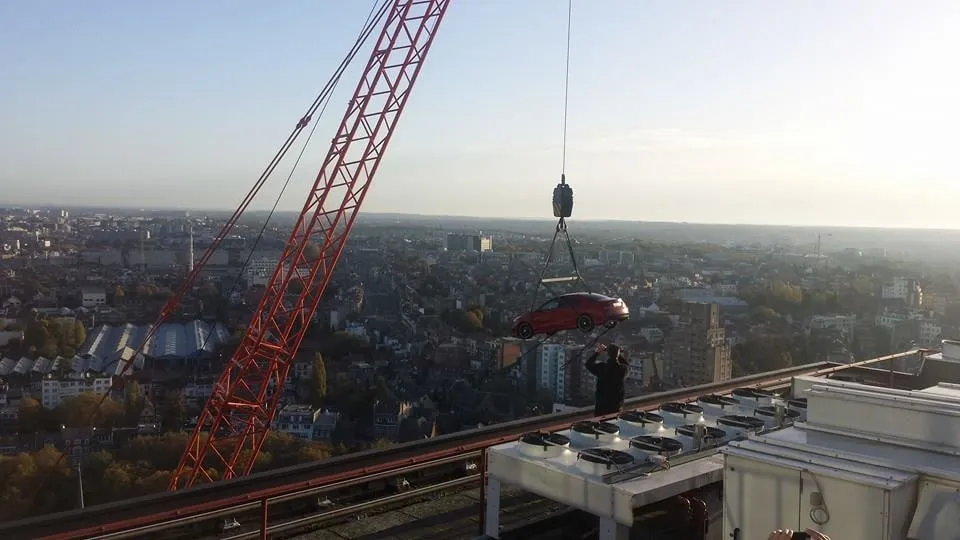Wagen hangend aan een bouwkraan hoog boven de daken van een stad