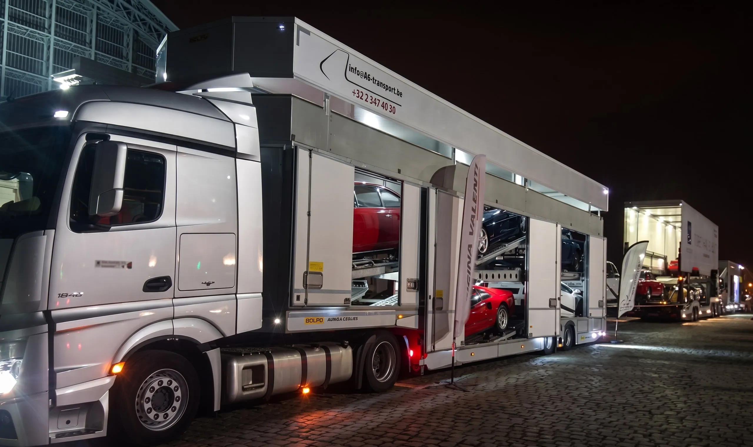 Camion porte-voitures éclairé de nuit dans un paddock
