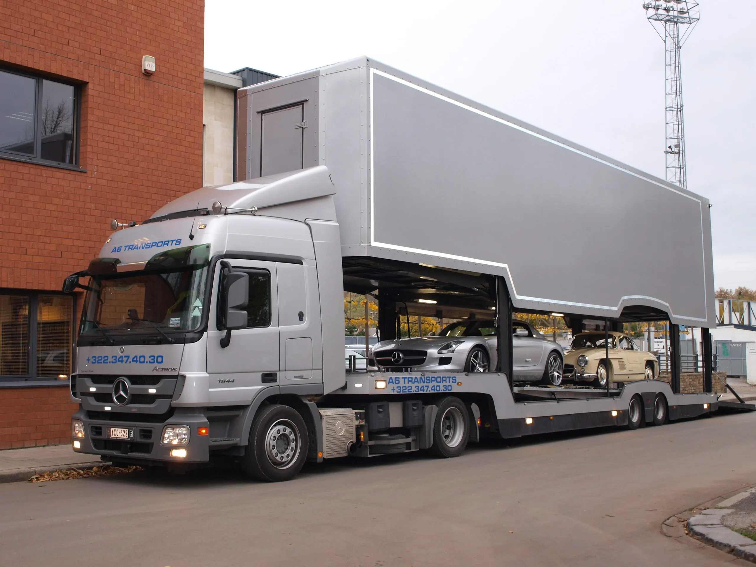 Gesloten transporter geladen met klassieke Mercedessen, driekwart vooraanzicht