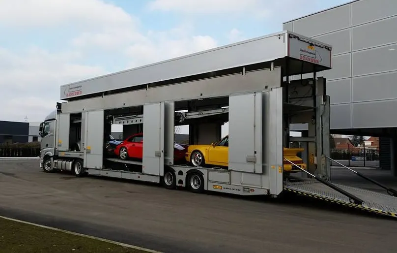 Gesloten transporter met open zijdeuren, wagens zichtbaar op beide dekken