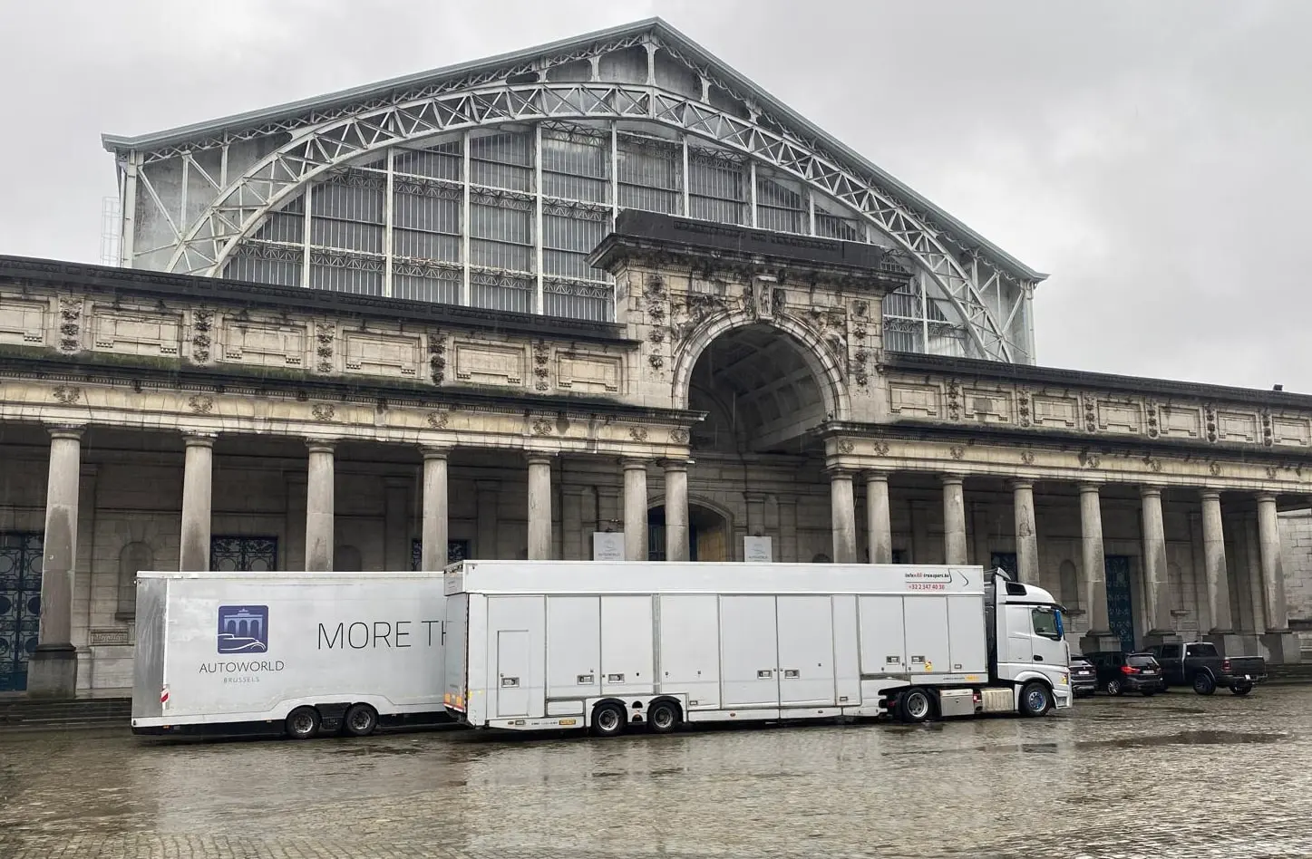 Due semirimorchi chiusi davanti alla sala di Autoworld al Cinquantenaire, uno nei colori del museo, sotto la pioggia