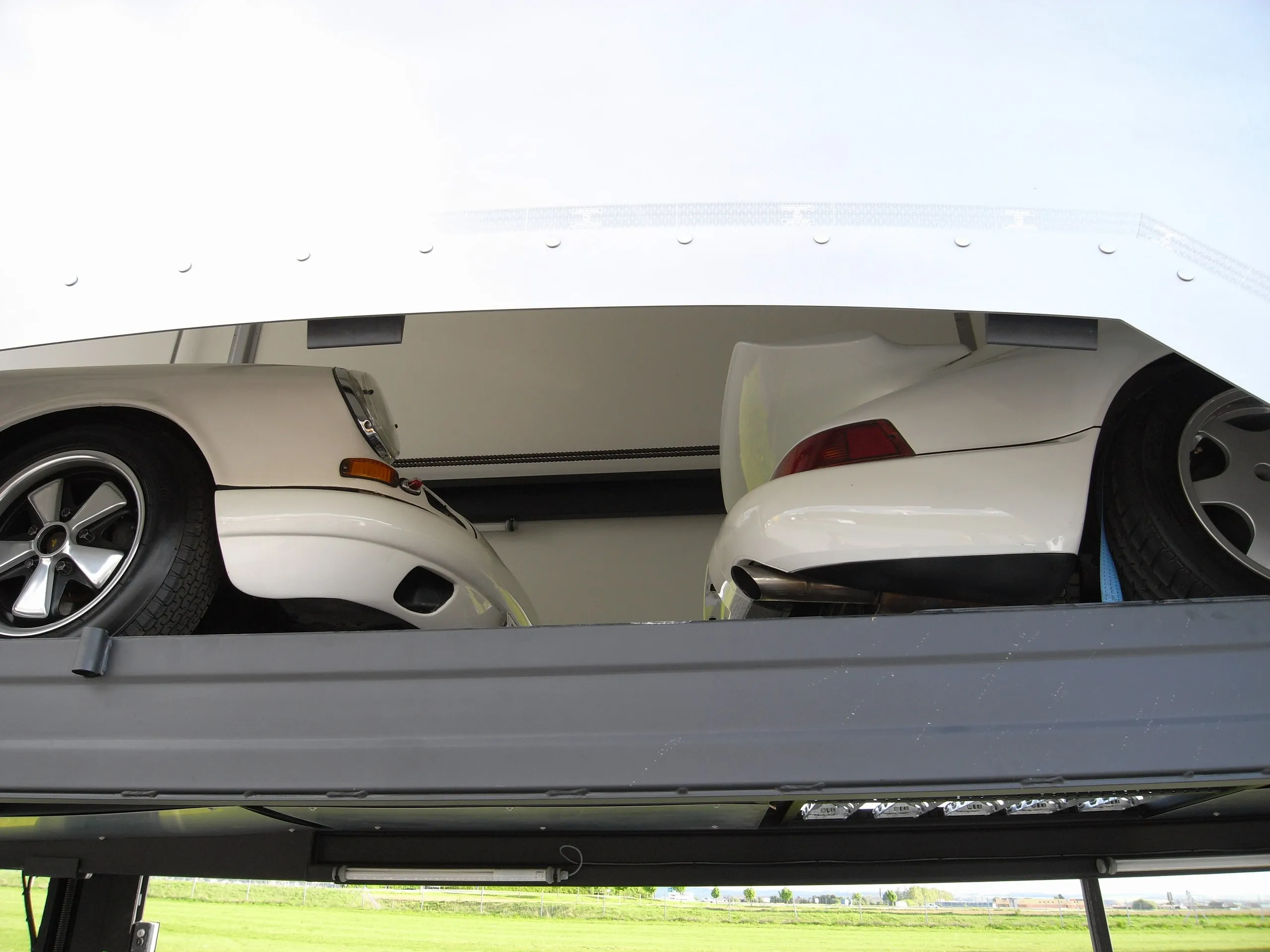 Twee witte Porsche 911's achter elkaar onder het opgeheven bovendek